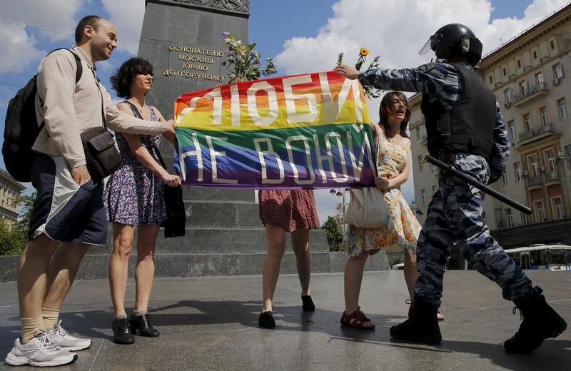 Участники митинга в поддержку прав ЛГБТ-сообщества держат радужный флаг в то время, как сотрудник полиции пытается их остановить. Центр Москвы, 30 мая 2015 г. 