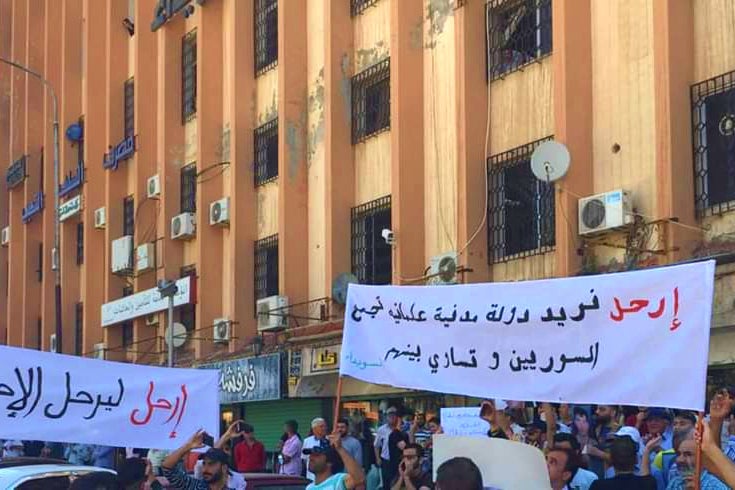 People hold up banners at a protest in Sweida on June 9, 2020 