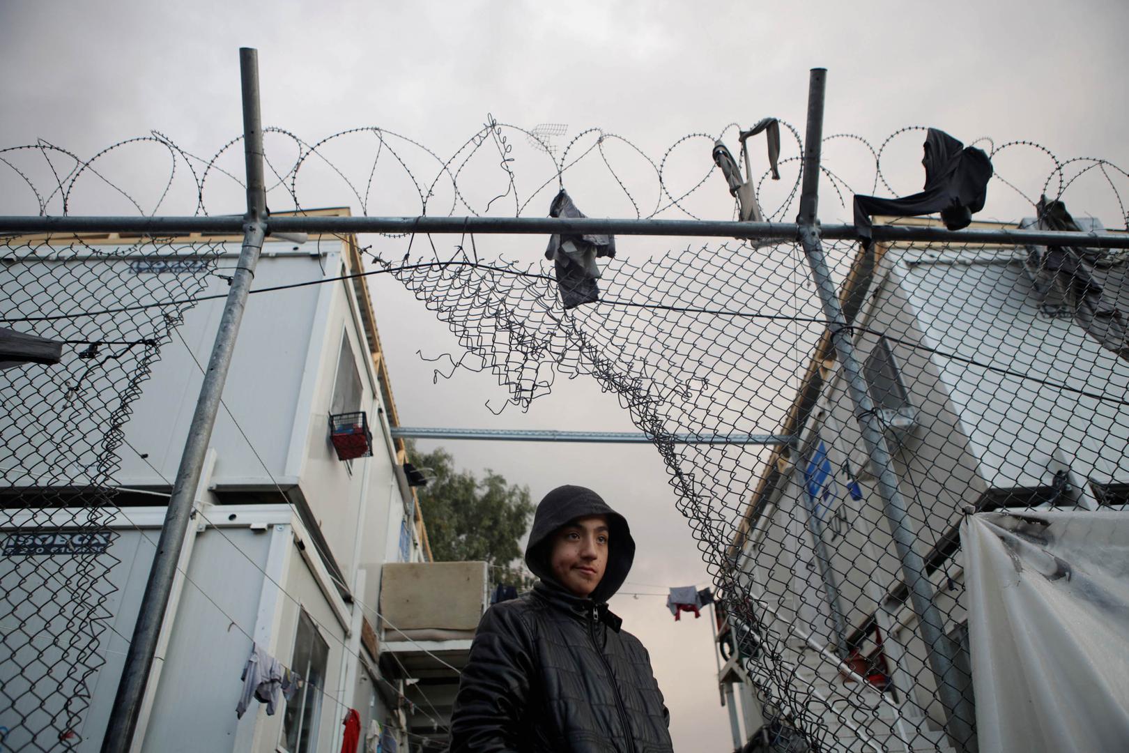 A boy stands next to a hole in the fence of the Moria camp following rainfall, on the island of Lesbos, Greece, November 22, 2019. 