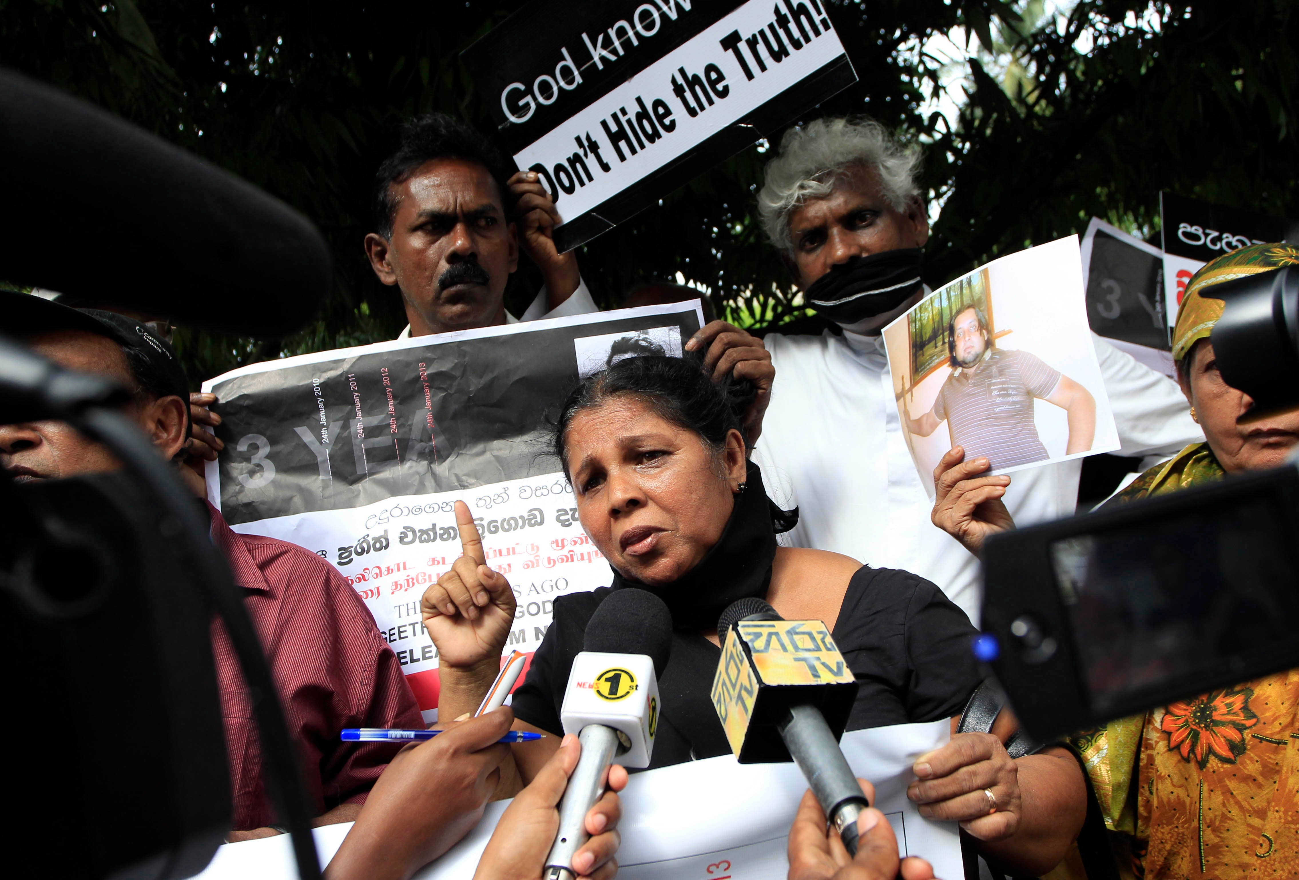 A woman speaking to reporters holding microphones