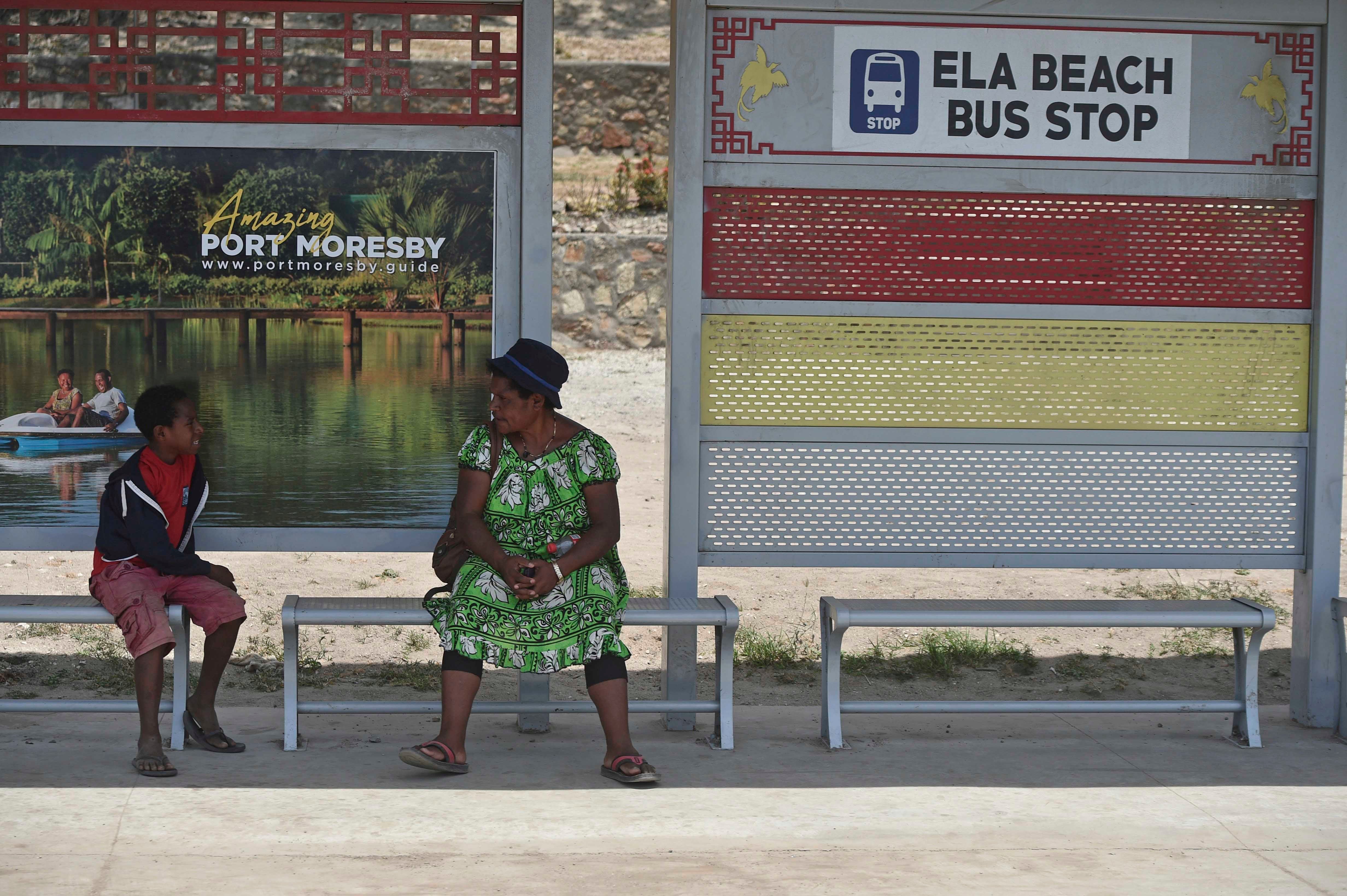 A boy and a woman at a bus stop in Port Moresby.
