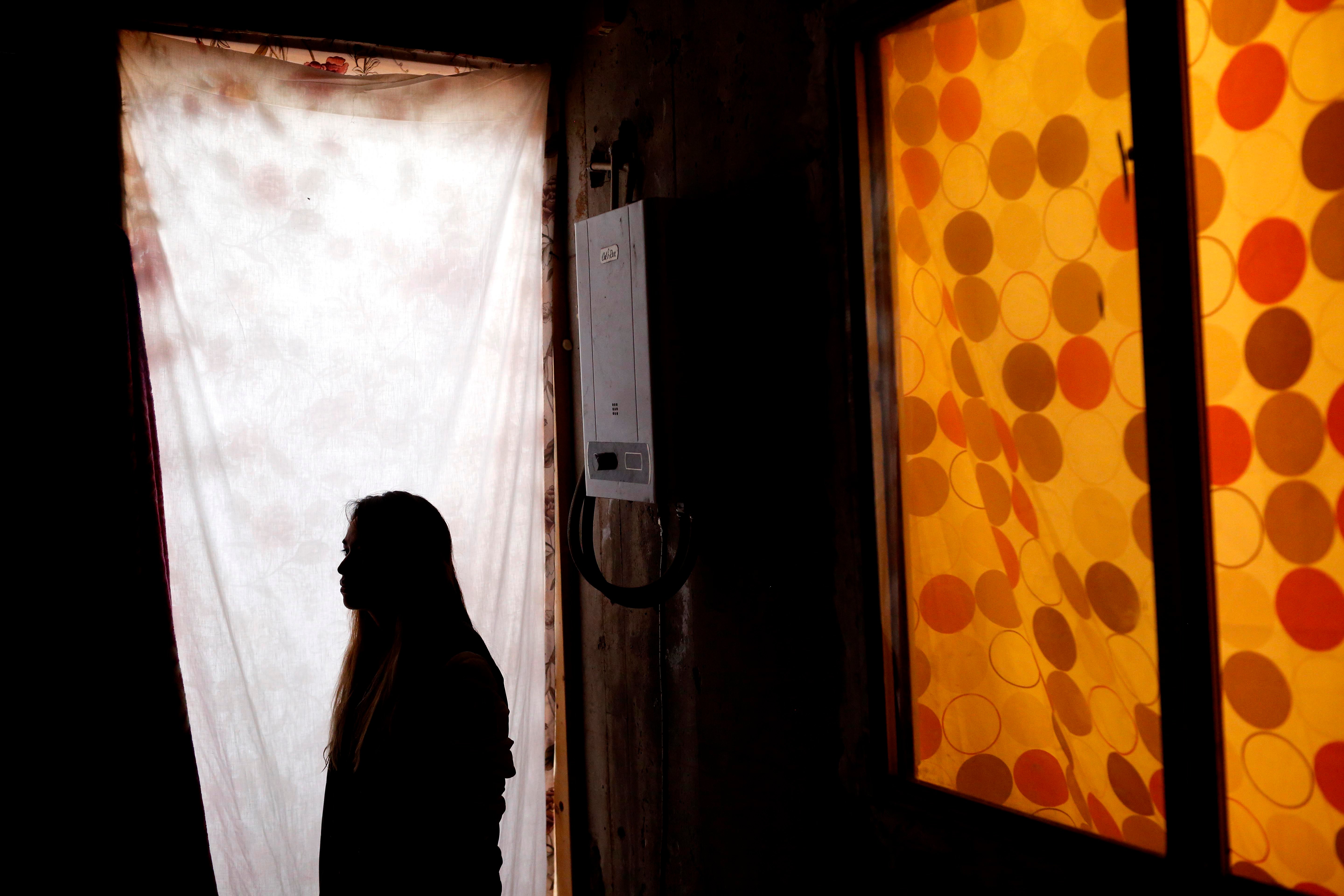 Woman stands in profile with in a doorframe, her face is obscured