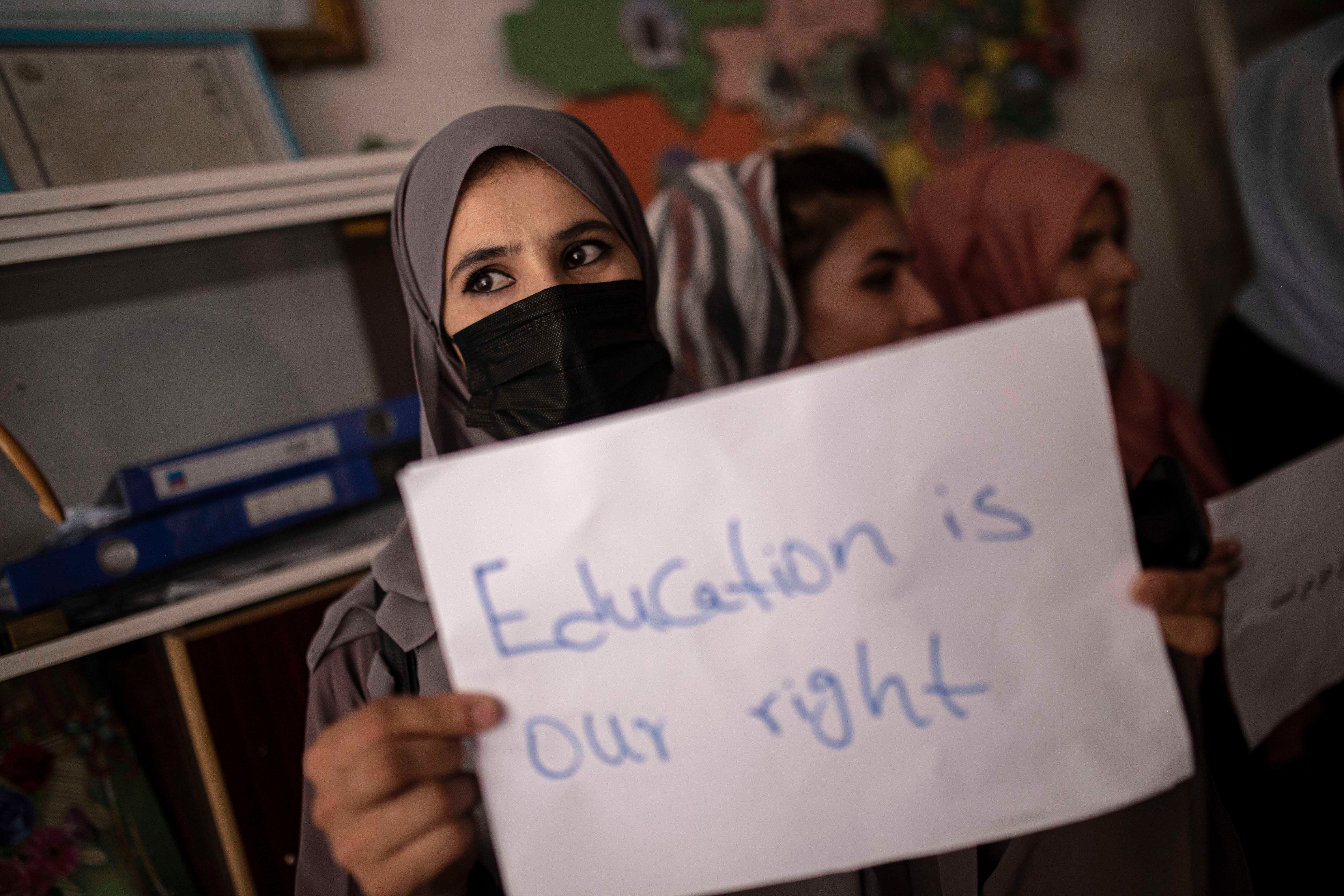 A woman holds a protest sign that reads "Education is our right"