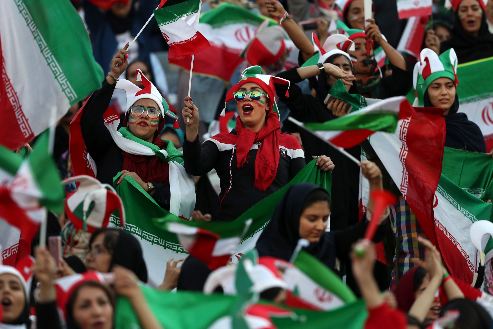 Women cheer holding flags and wearing face paint
