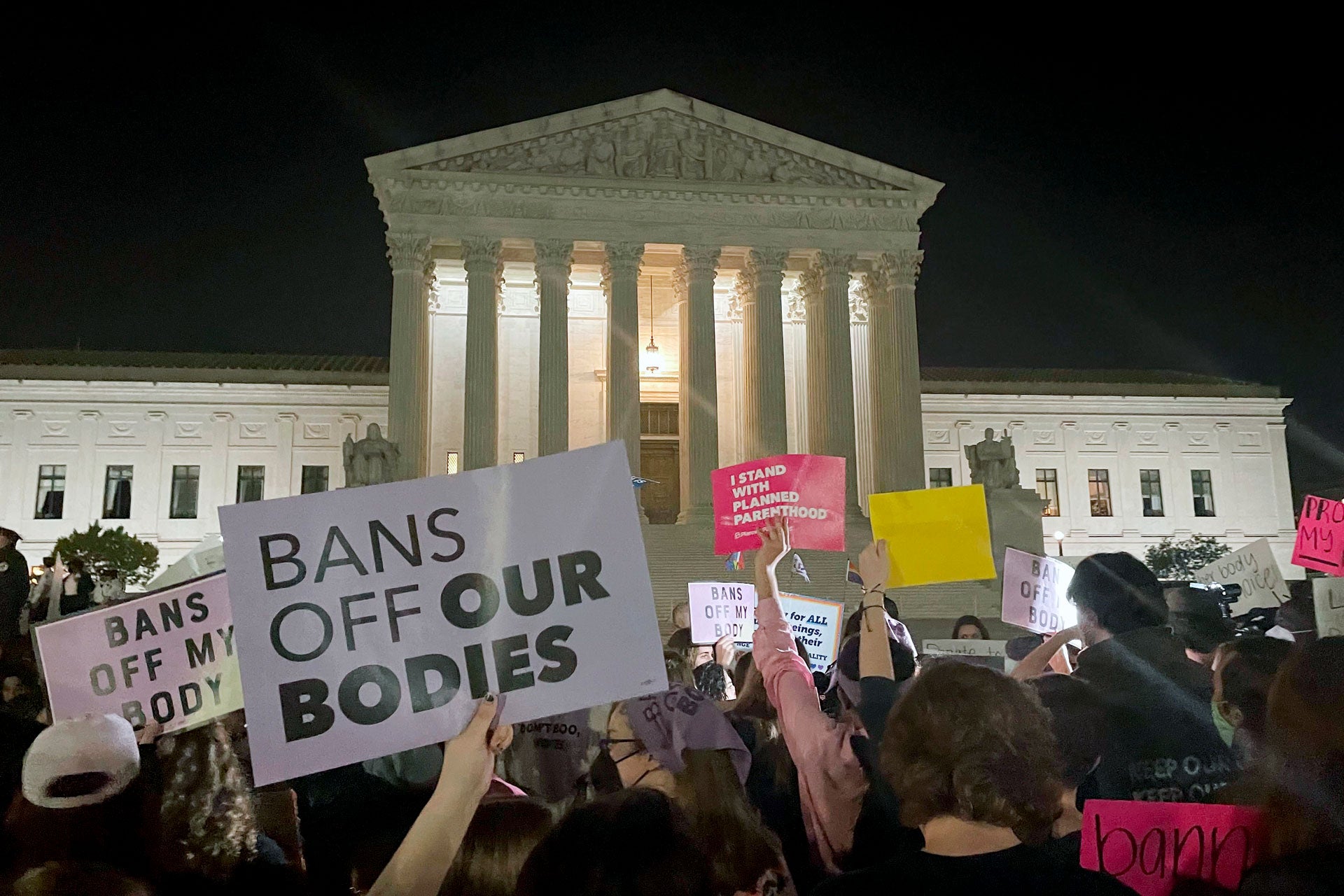 Manifestation devant la Cour suprême des États-Unis à Washington, dans la soirée du 2 mai 2022, peu après la divulgation par un site d’informations que la Cour pourrait annuler l’arrêt « Roe versus Wade » qui garantit le droit à l’avortement. Message sur la pancarte : « Pas d’interdictions visant nos corps ».