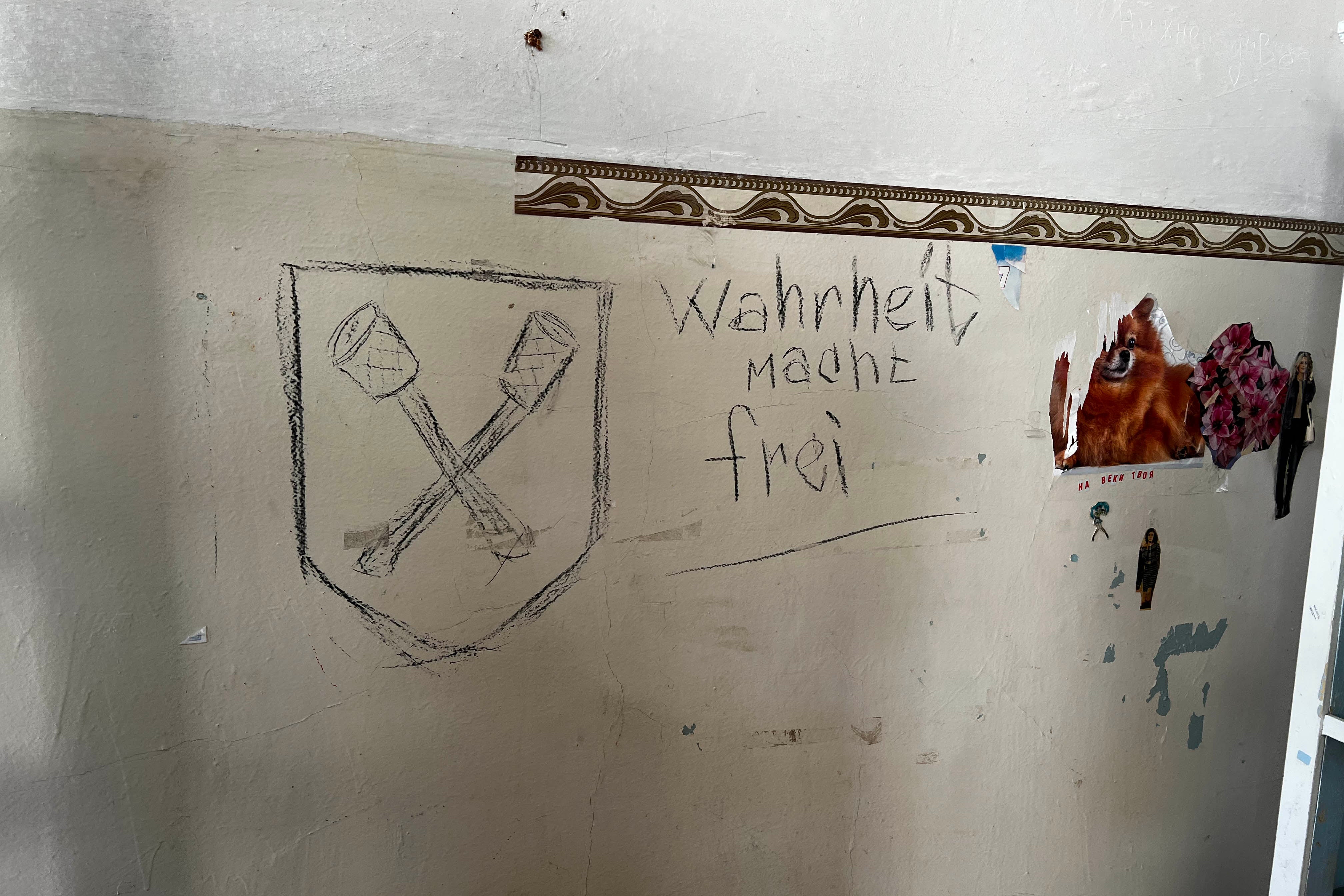 Напис німецькою «Правда звільняє» на стіні в одному з кабінетів міської залізничної поліклініки, а також емблема, яка може зображати схрещені рукоятки гранат, яка була символом бригади Дірлевангера – німецької бригади СС часів Другої світової війни, м. Ізюм, Україна, 22 вересня 2022 р