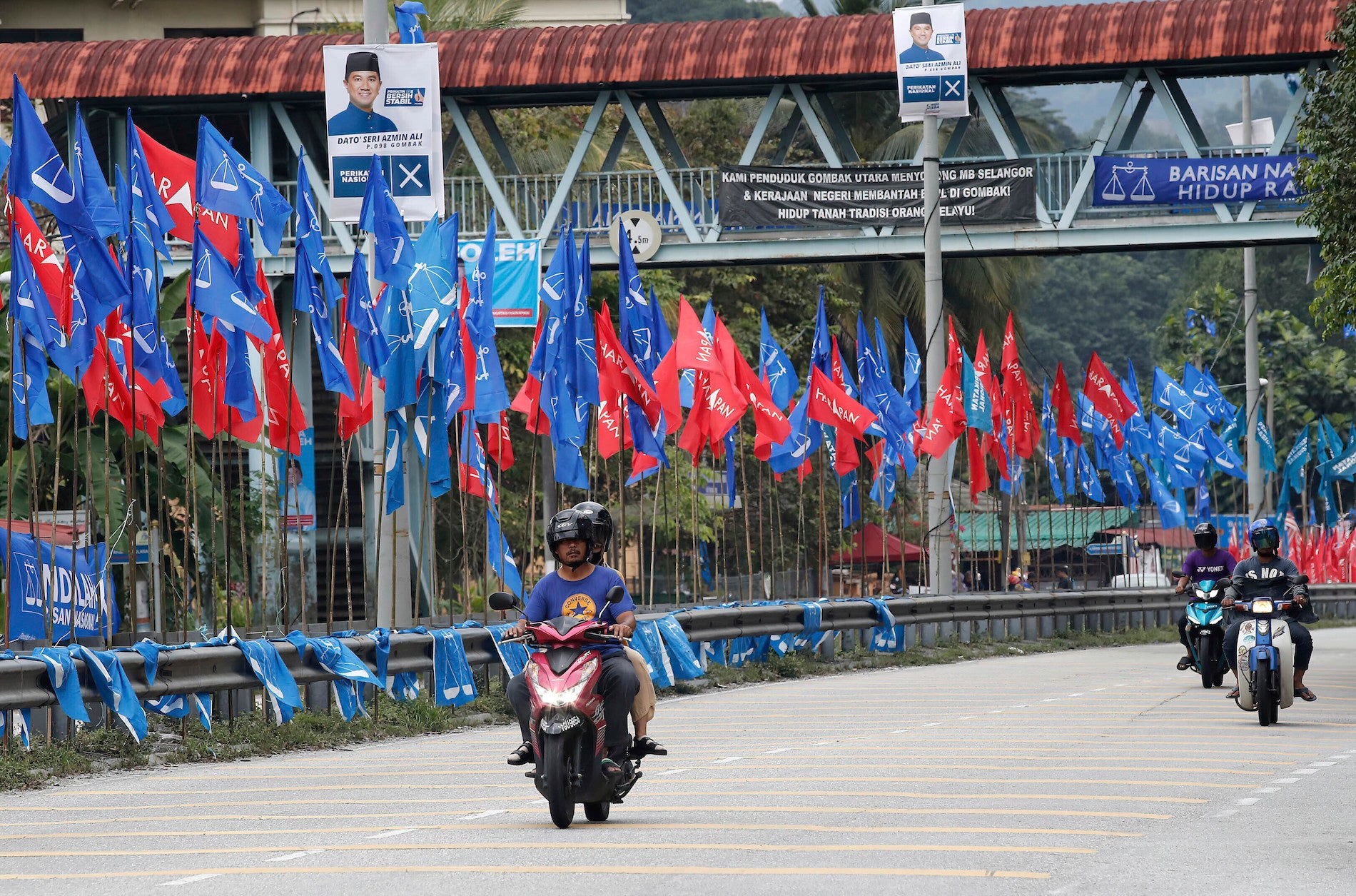 Motorcyclists ride past political party flags in Kuala Lumpur.