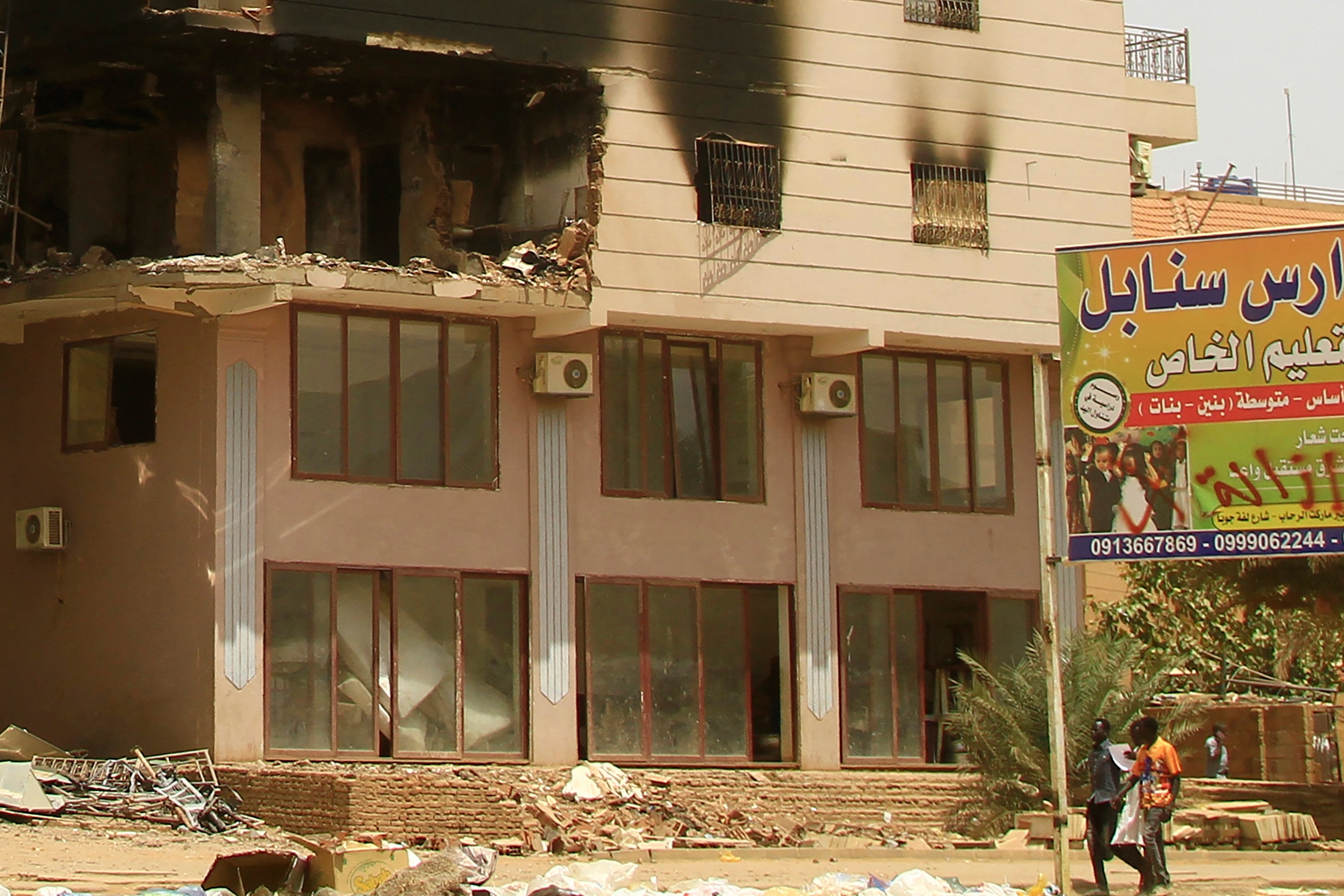 Men walk by a damaged building