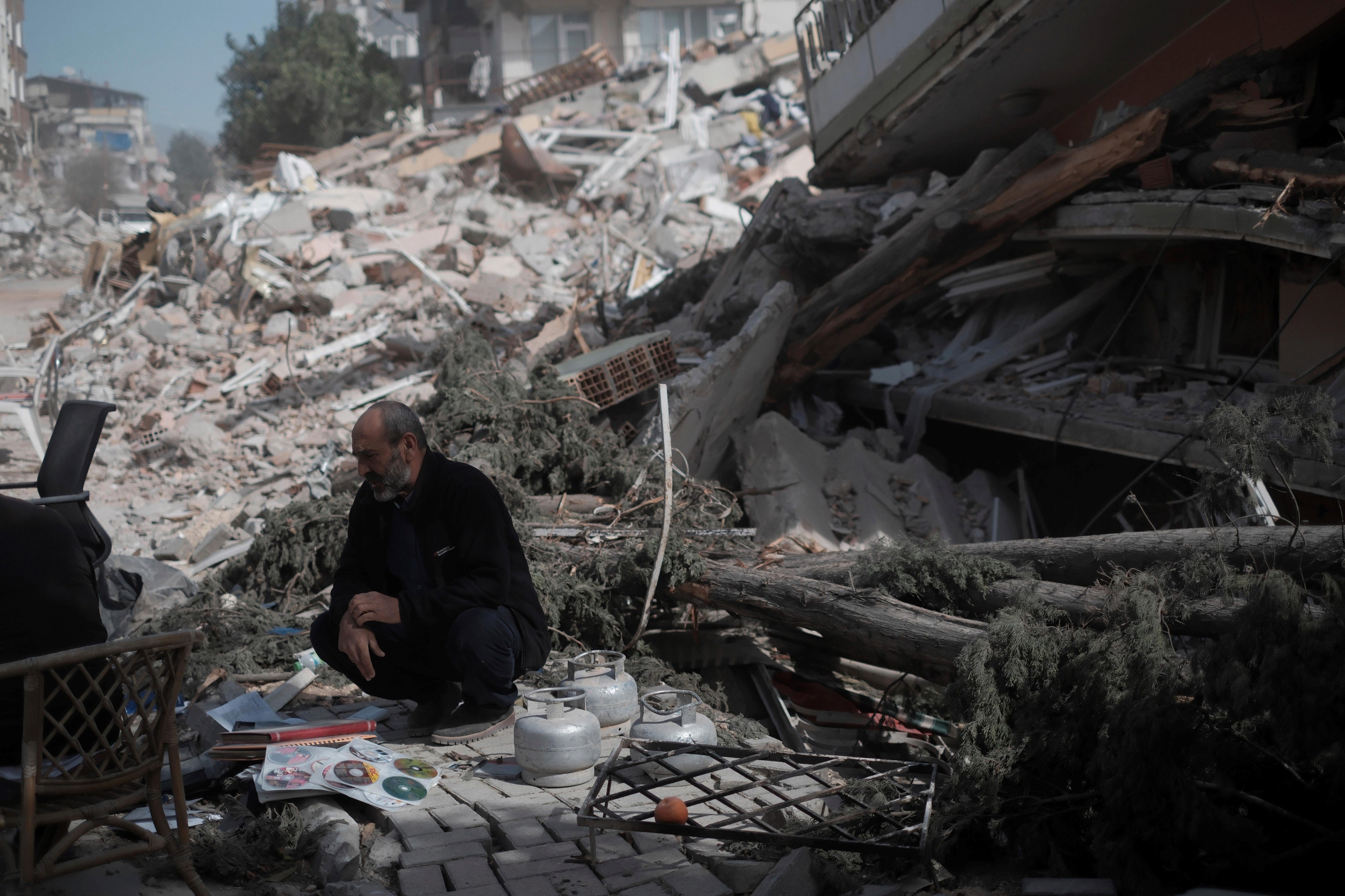 A man beside the rubble of a building in Antakya, southern Türkiye, on March 6, 2023, one month after the devastating earthquakes in which over 50,000 people died and hundreds of thousands were injured and displaced.