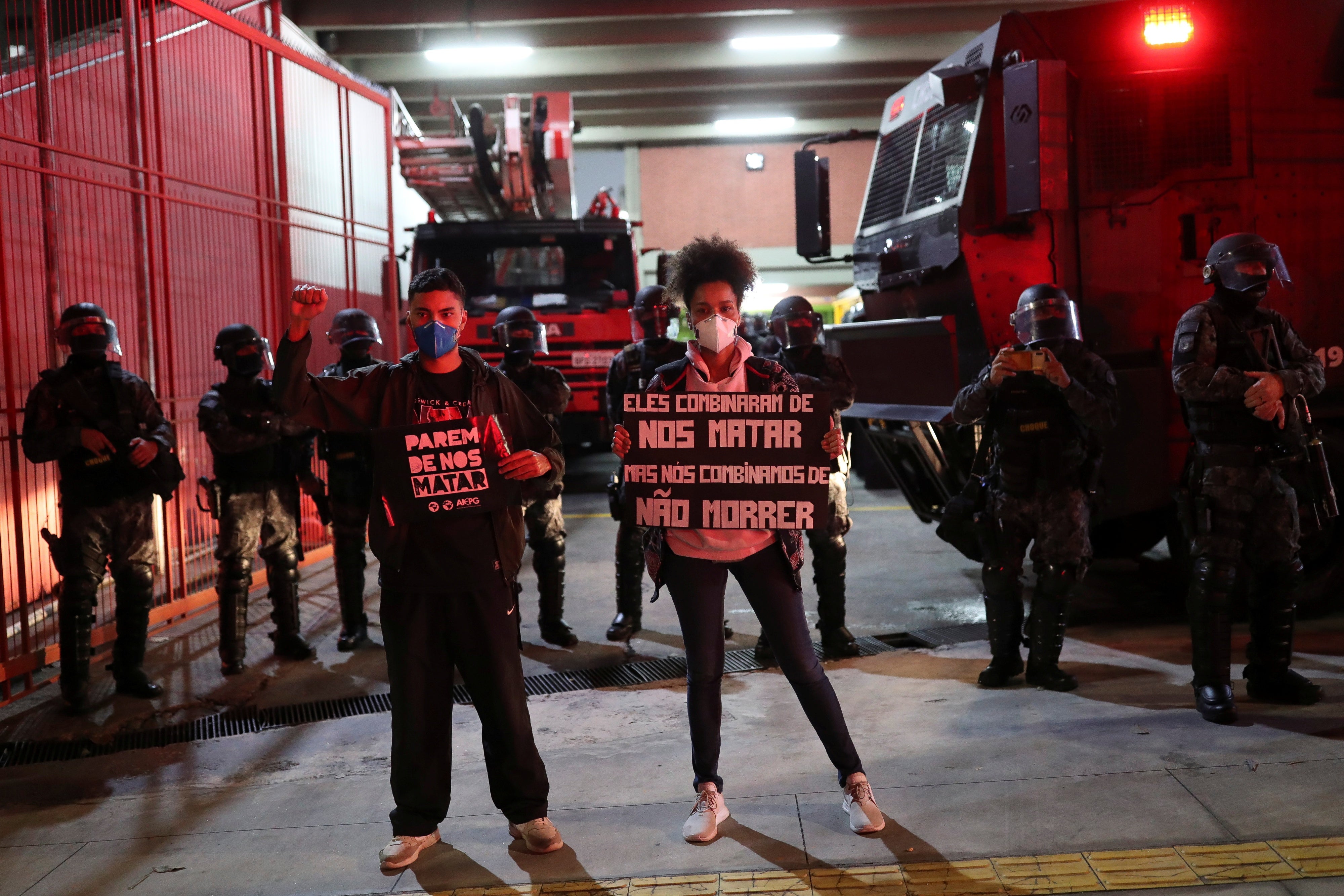 Ativistas protestam em São Paulo contra o racismo, a violência policial e uma operação policial que ocorreu no Jacarezinho, no Rio de Janeiro, Brasil, em 13 de maio de 2021. Os cartazes dizem “Parem de nos matar” e “Eles combinaram de nos matar, mas nós combinamos de não morrer”. 