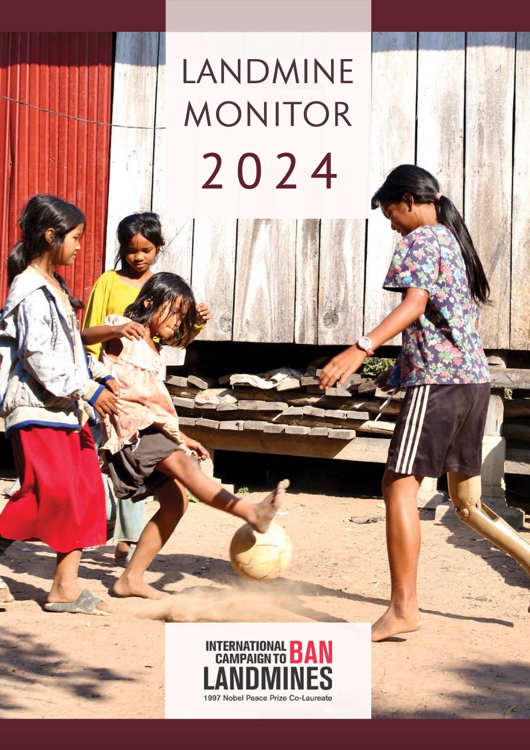 Three young girls play soccer in Cambodia. One girl who lost her leg from a landmine explosion is playing with a prosthetic leg. 