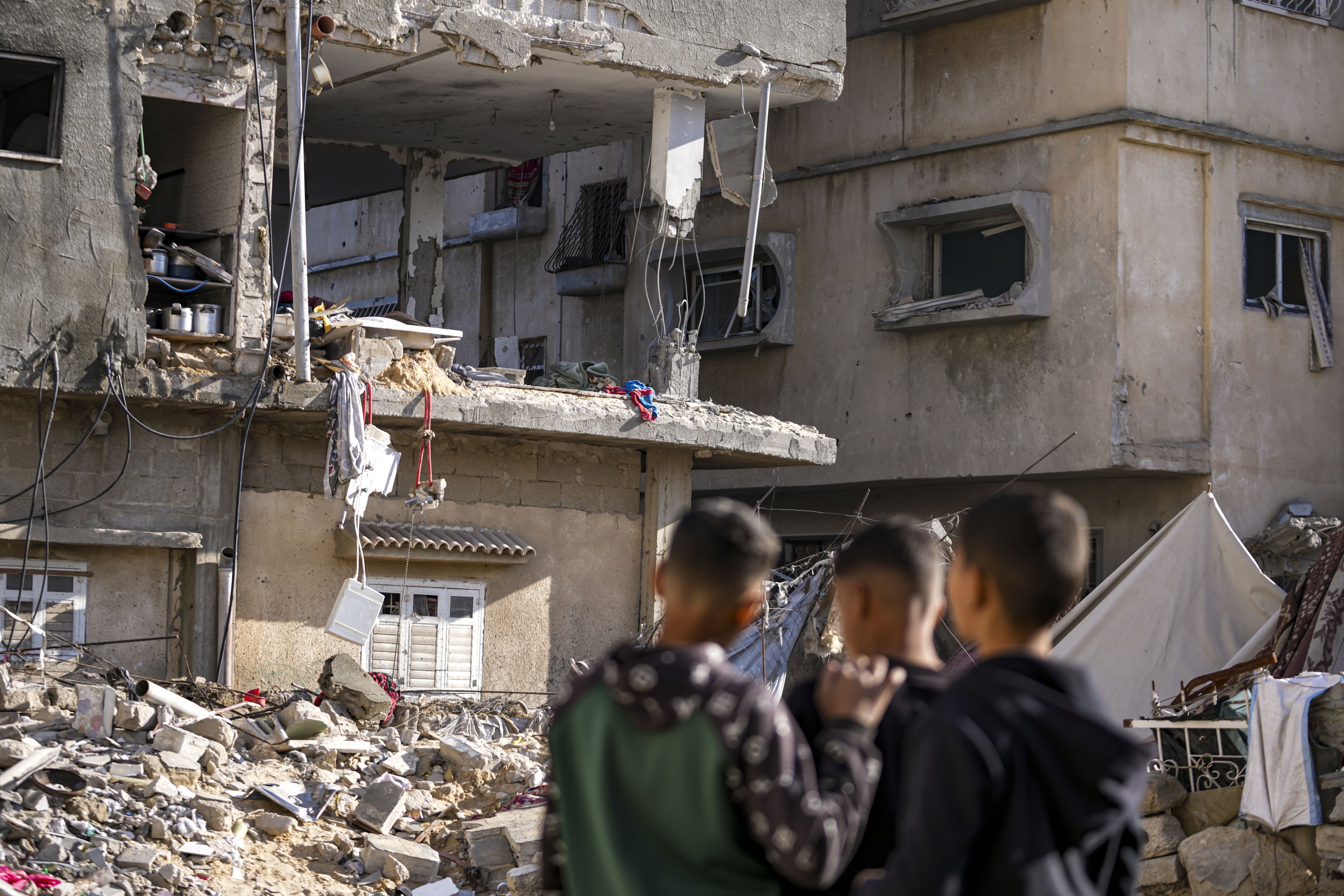 Três homens olham para um prédio danificado destruído por um ataque israelense.