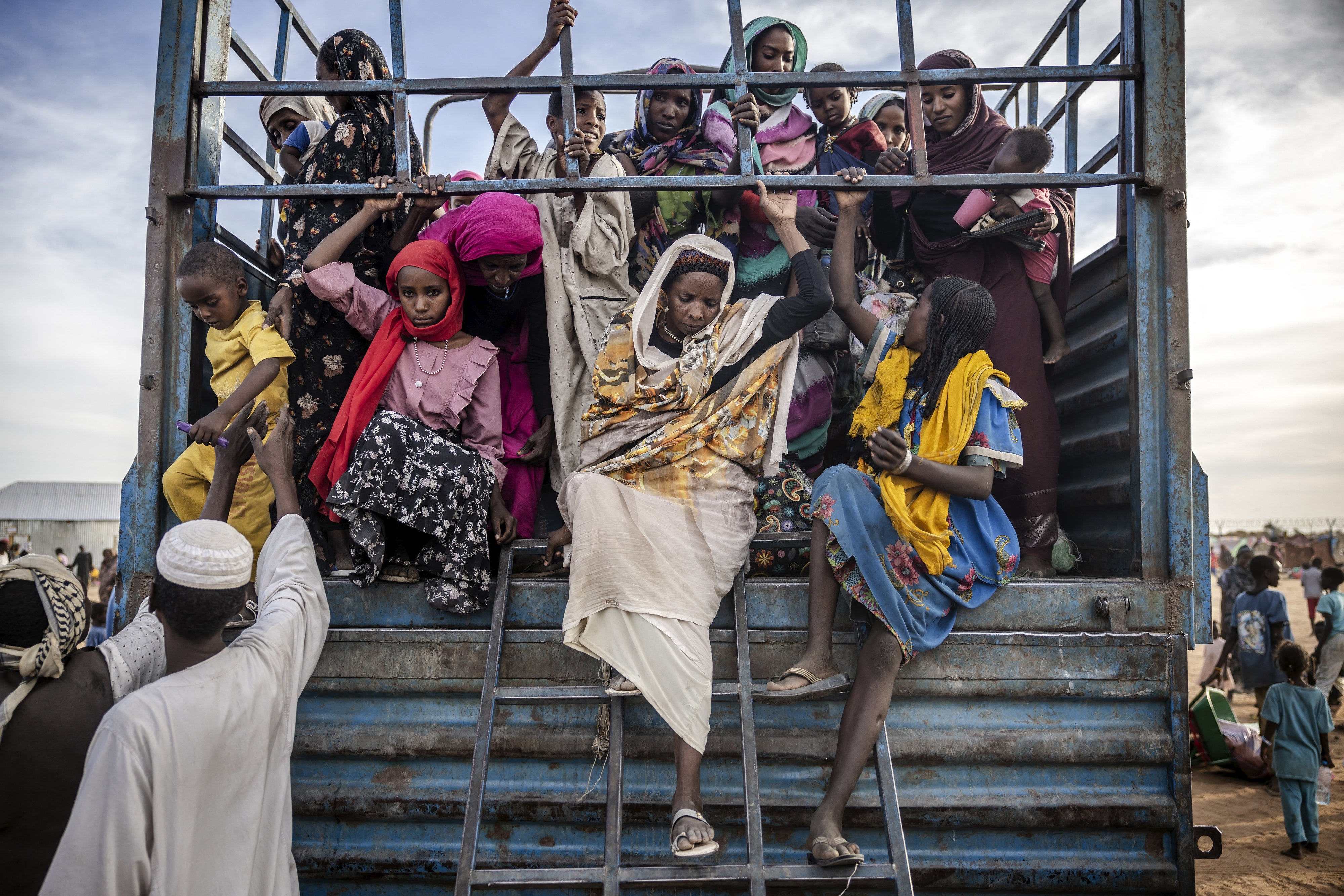 refugees get off a truck loaded with families