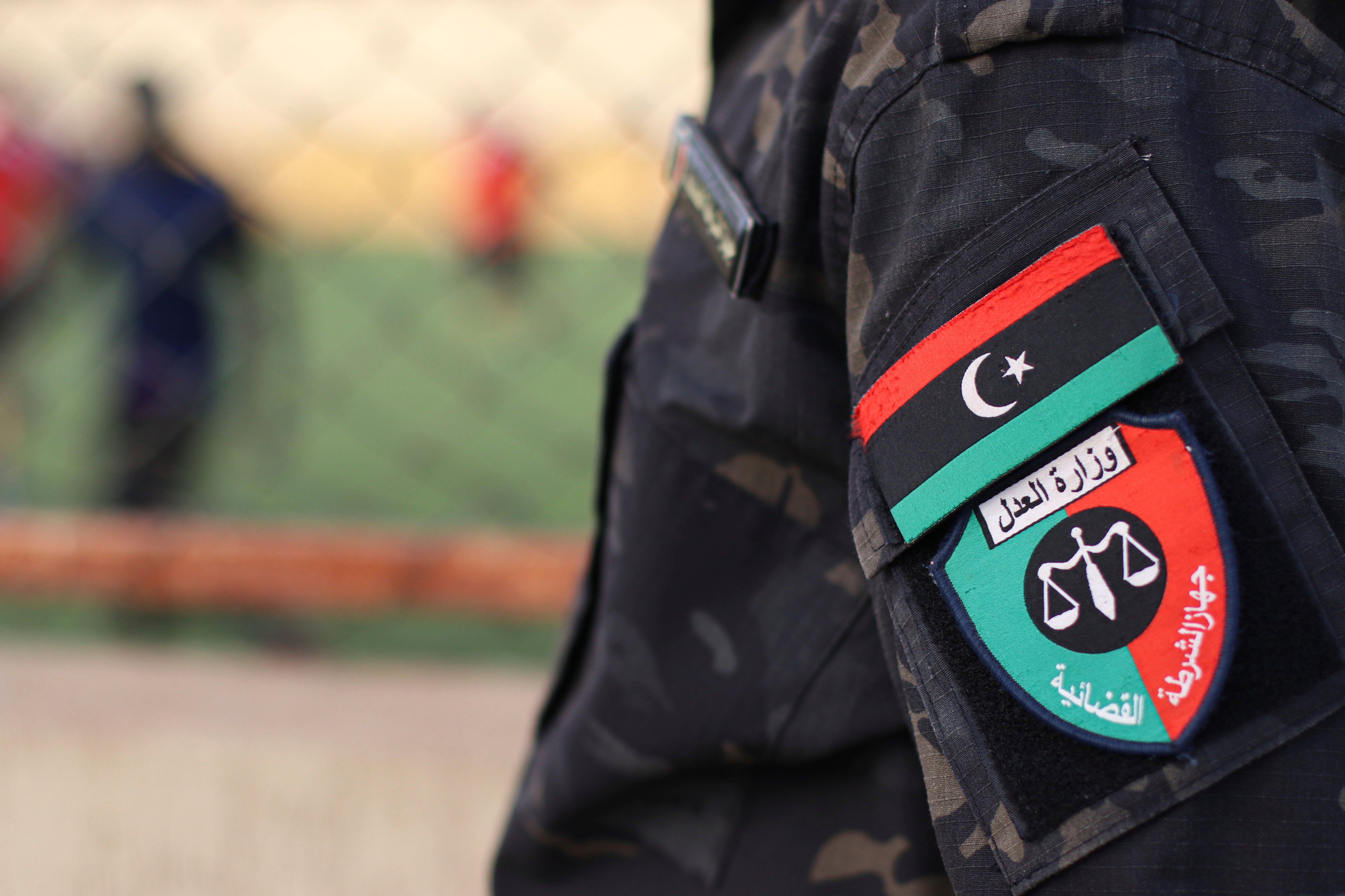 An emblem on the uniform of a judicial police guard standing at a prison