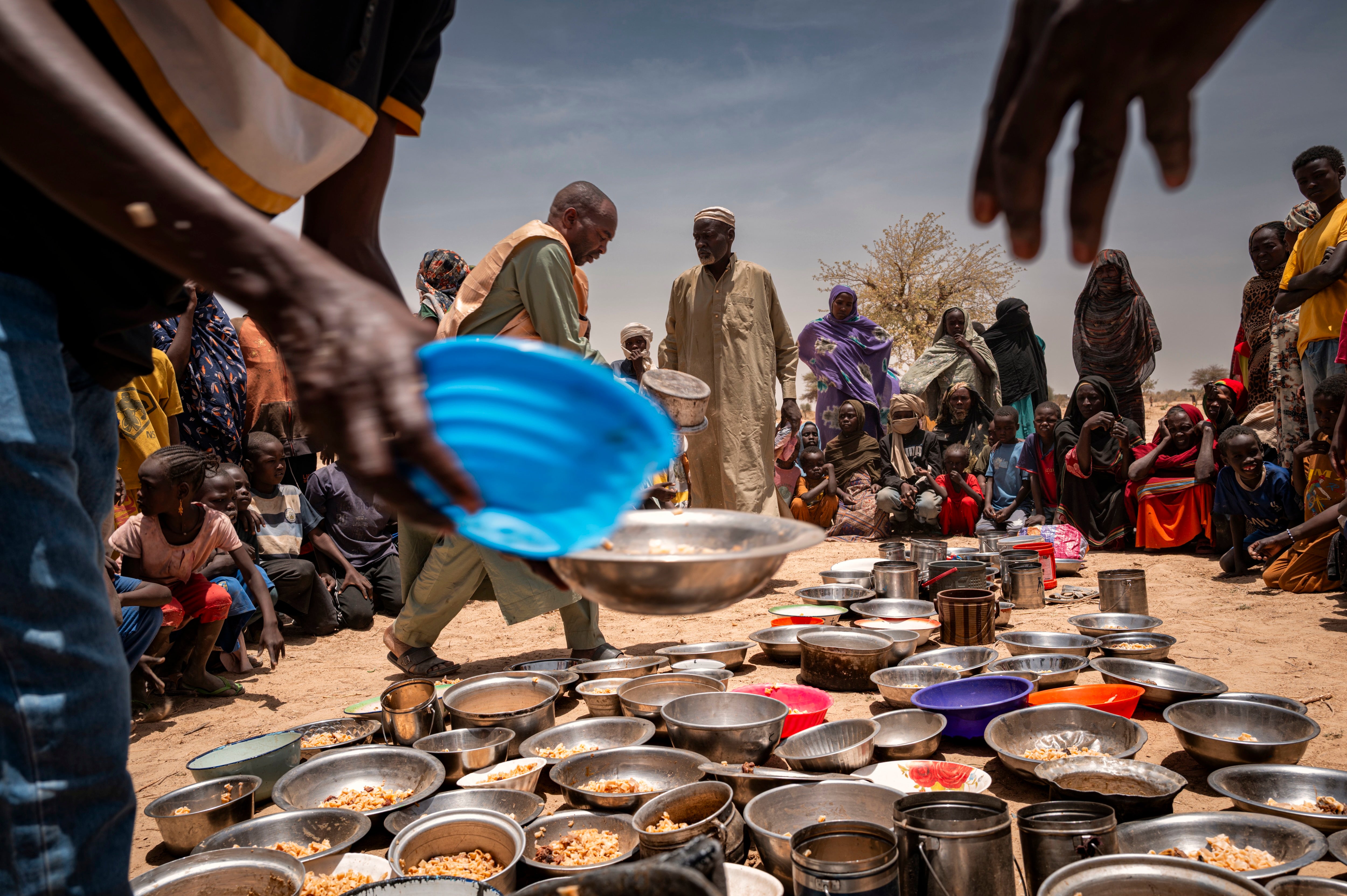 لاجئون سودانيون من مخيم زمزم في جوار الفاشر، في دارفور، يتلقون الطعام في مطبخ مجتمعي (تكية) تابع لـ "غرف الطوارئ" أثناء نقلهم إلى مخيم أردمي في تين، شرق تشاد، 4 مايو/أيار 2025.