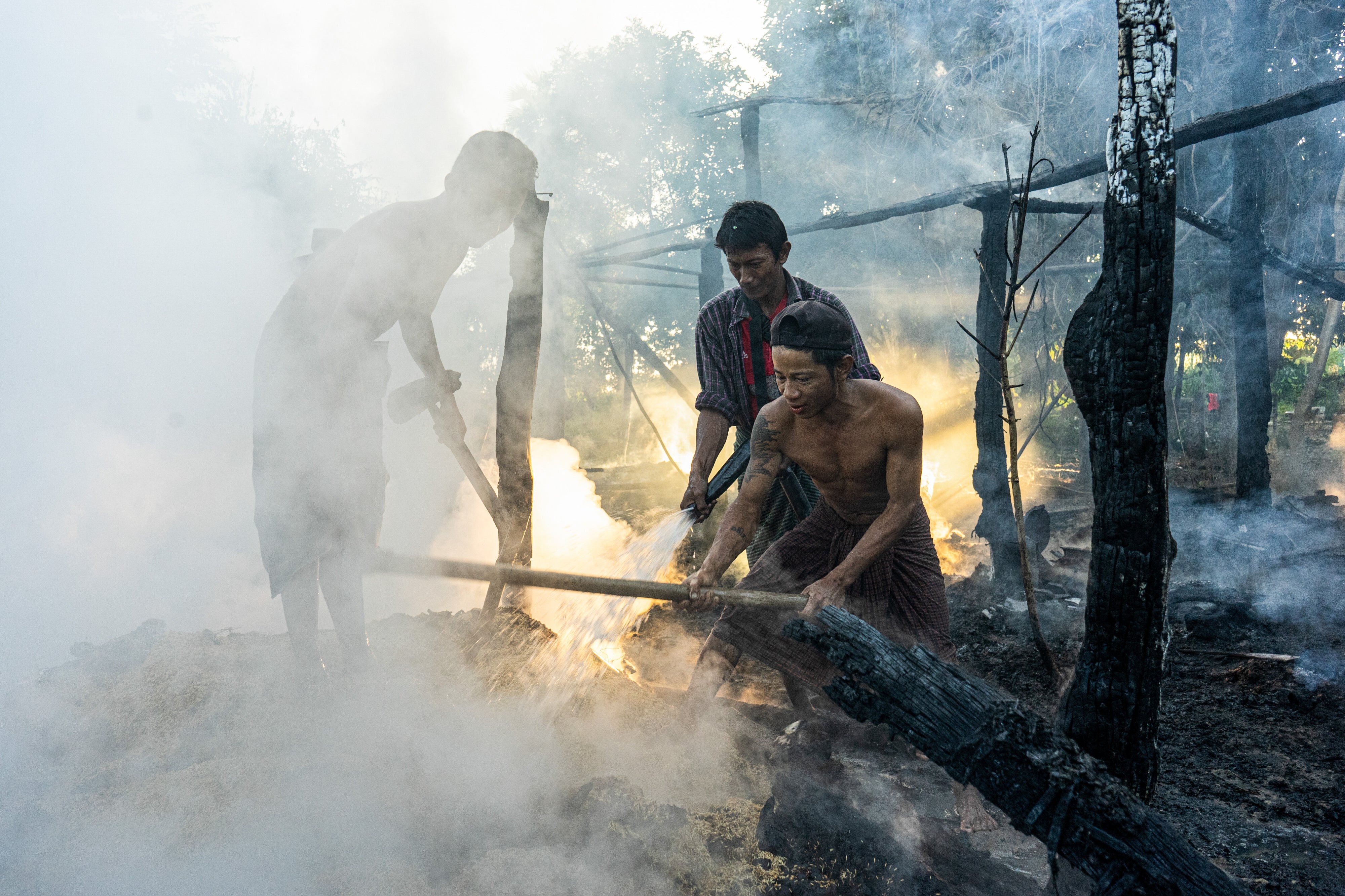 Des villageois éteignaient les restes d’un incendie ayant ravagé une maison, suite à une frappe aérienne menée par l'armée du Myanmar, à Tabayin, dans la région de Sagaing située dans le nord-ouest de ce pays, le 13 novembre 2025.