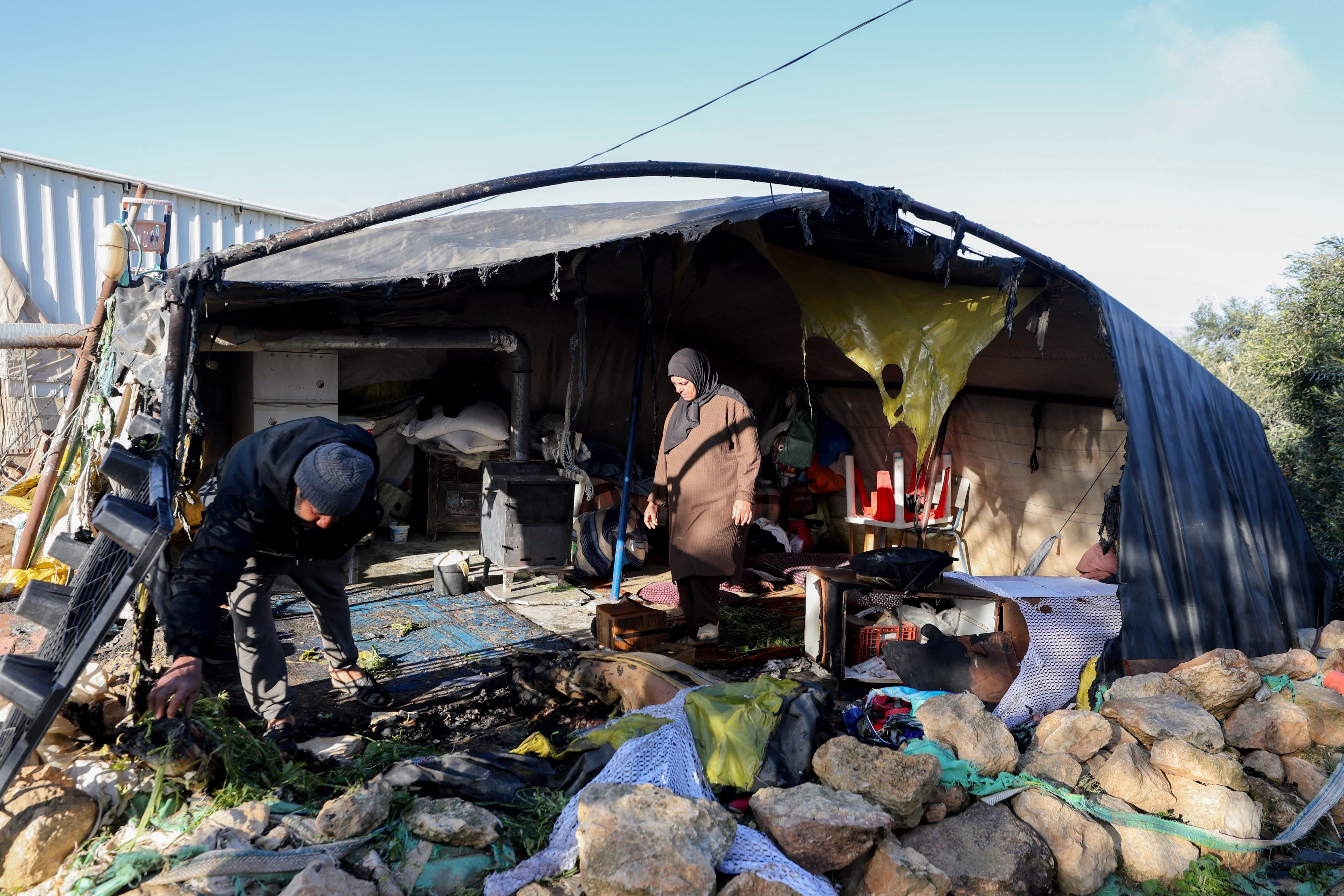 Anwohner*innen begutachten beschädigte Habseligkeiten in einem Zelt, das mutmaßlich von israelischen Siedlern im Dorf Susya in Masafer Yatta südlich von Hebron im von Israel besetzten Westjordanland in Brand gesetzt wurde, 25. Februar 2026.