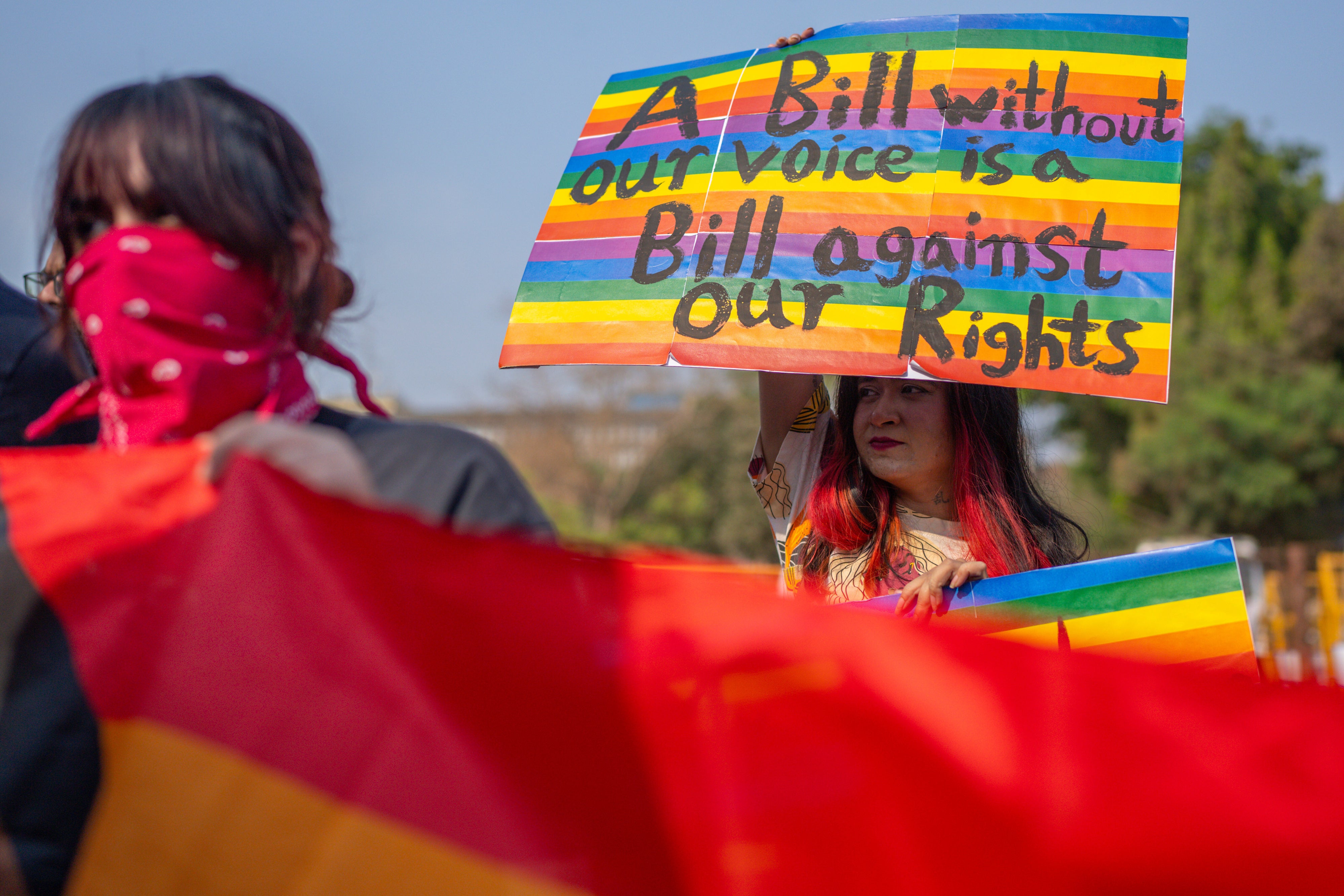 An activist holds a placard at a protest that reads "A bill without our voice is a bill against our rights"