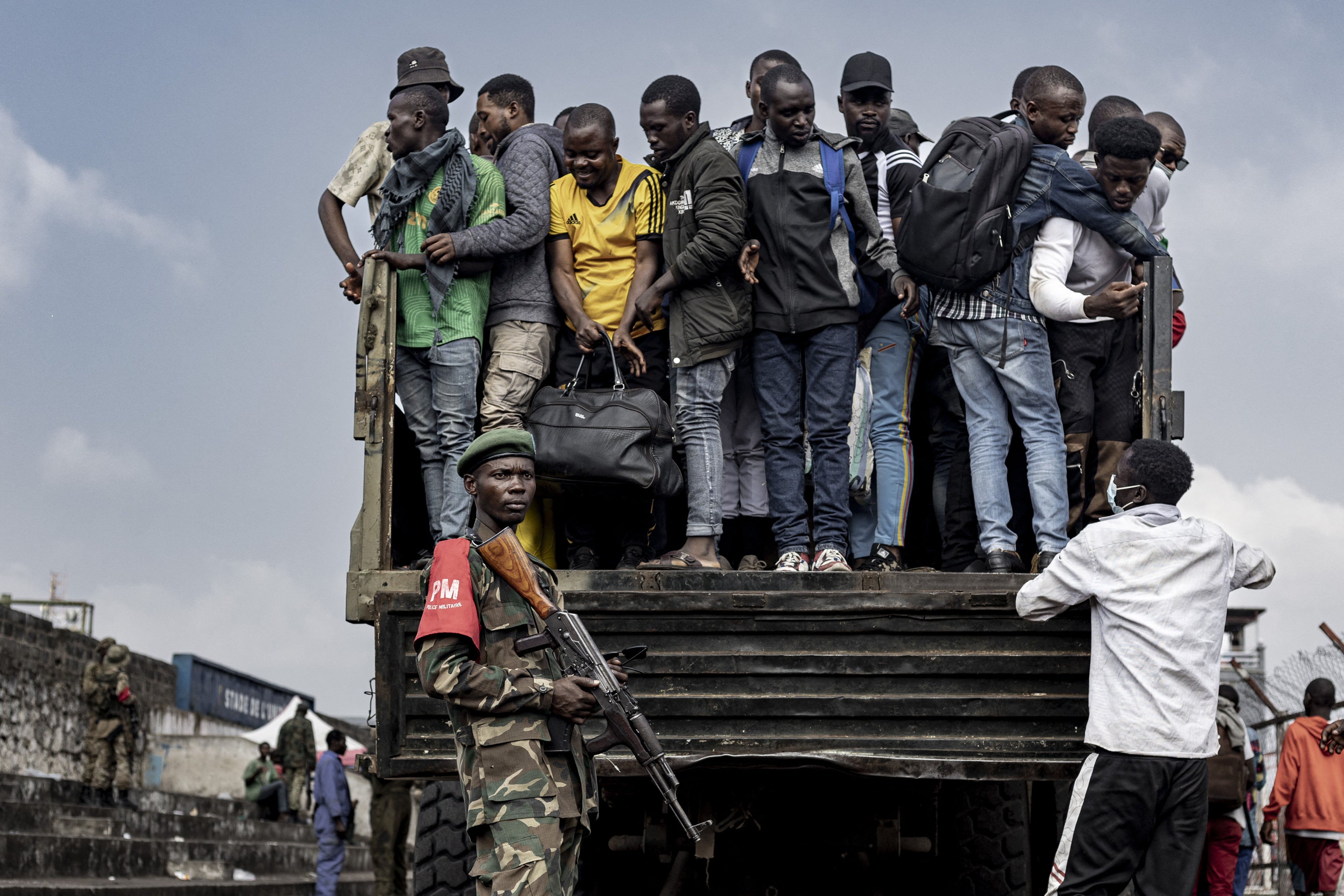 Un combattant du M23 monte la garde pendant que des personnes montent à bord d’un camion lors du recrutement de civils, de policiers, et d’anciens soldats de l’armée congolaise à Goma, en République démocratique du Congo, le 23 février 2025. 
