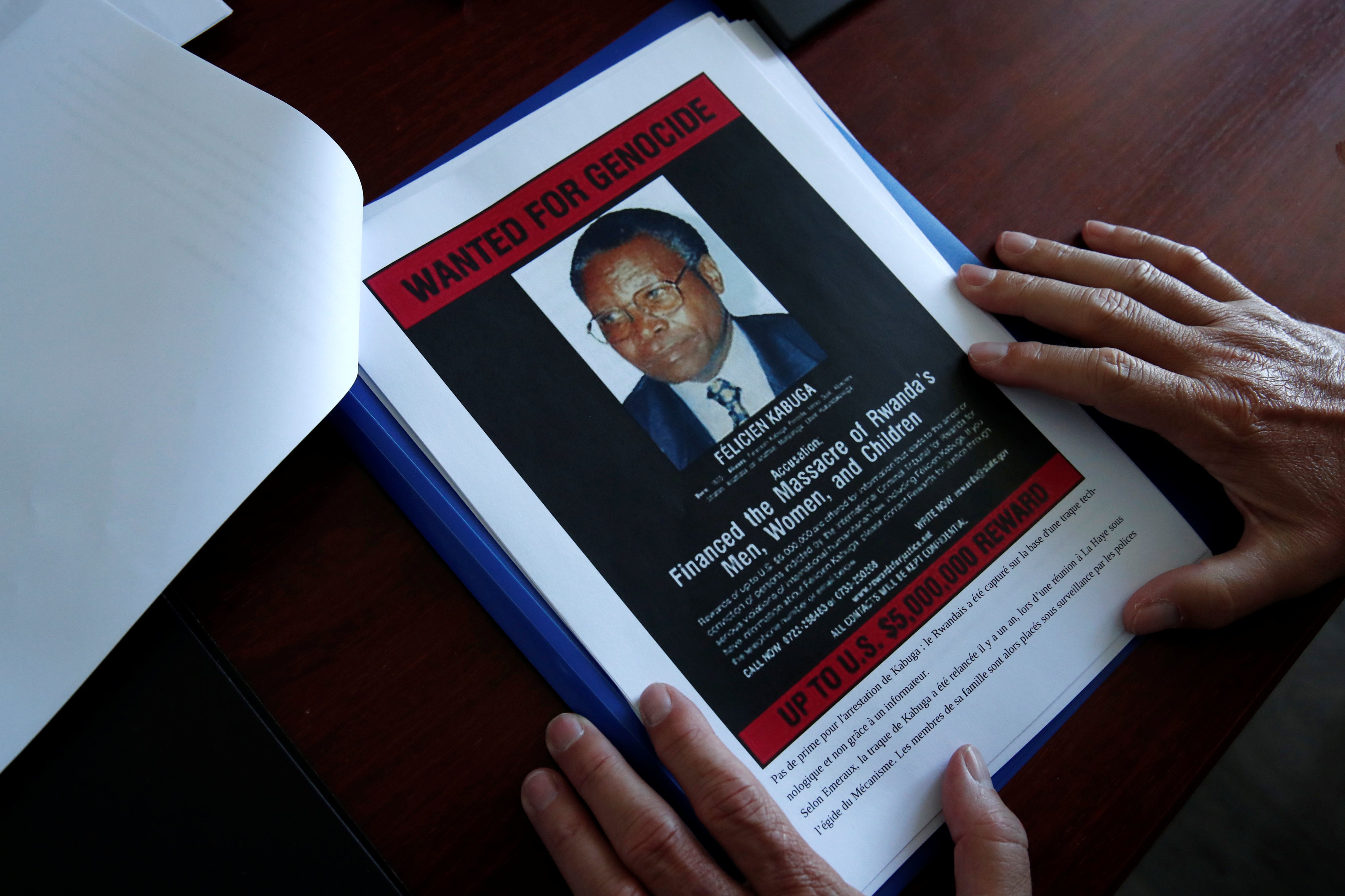 The head of the Gendarmerie’s Central Office for Combating Crimes Against Humanity, Genocides and War Crimes (OCLCH), displays documents with a wanted poster of Félicien Kabuga, May 19, 2020.