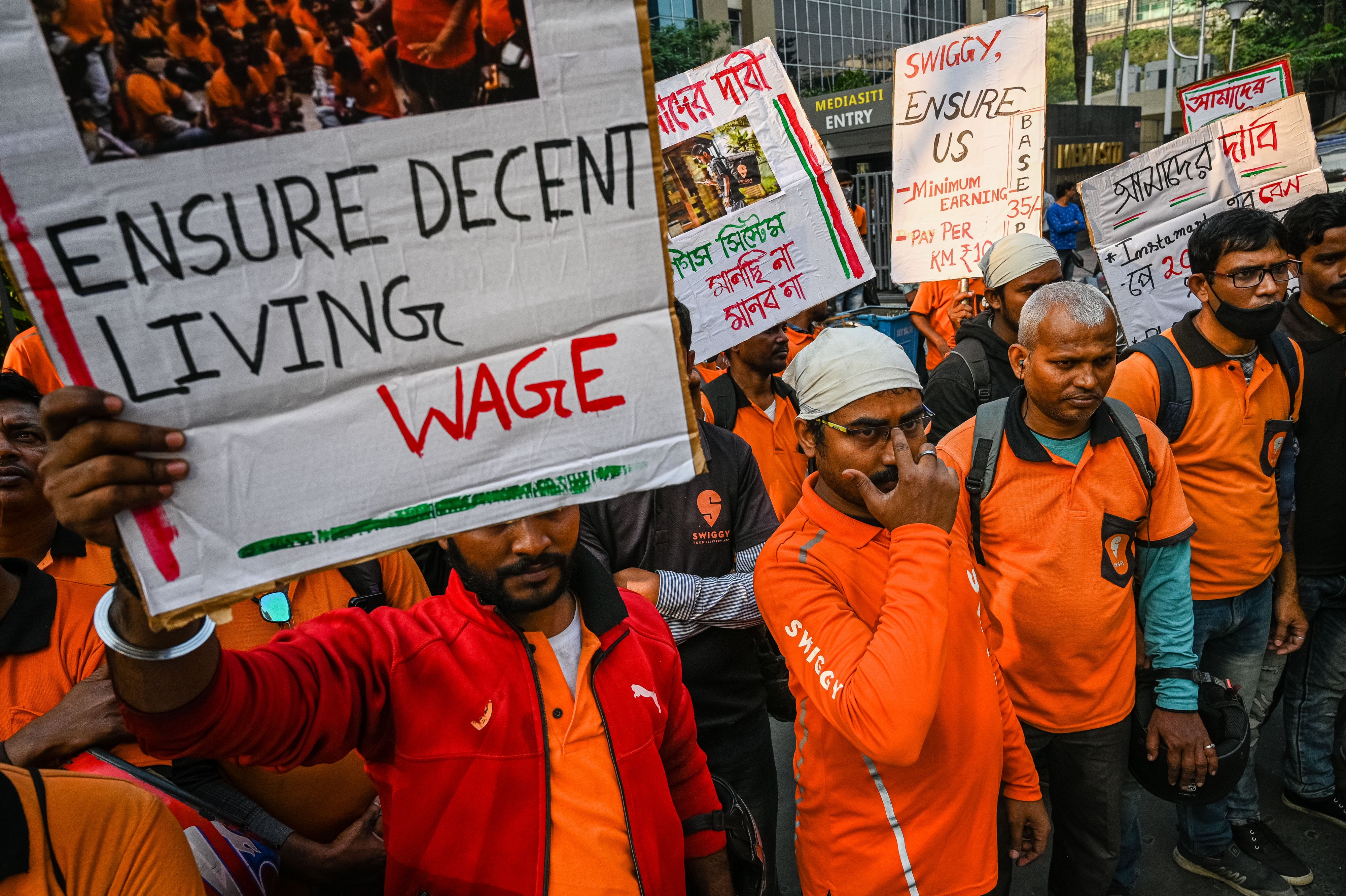 Delivery workers of an Indian food-delivery startup hold placards during a demonstration demanding a hike in their remuneration, in Kolkata, on November 22, 2022.