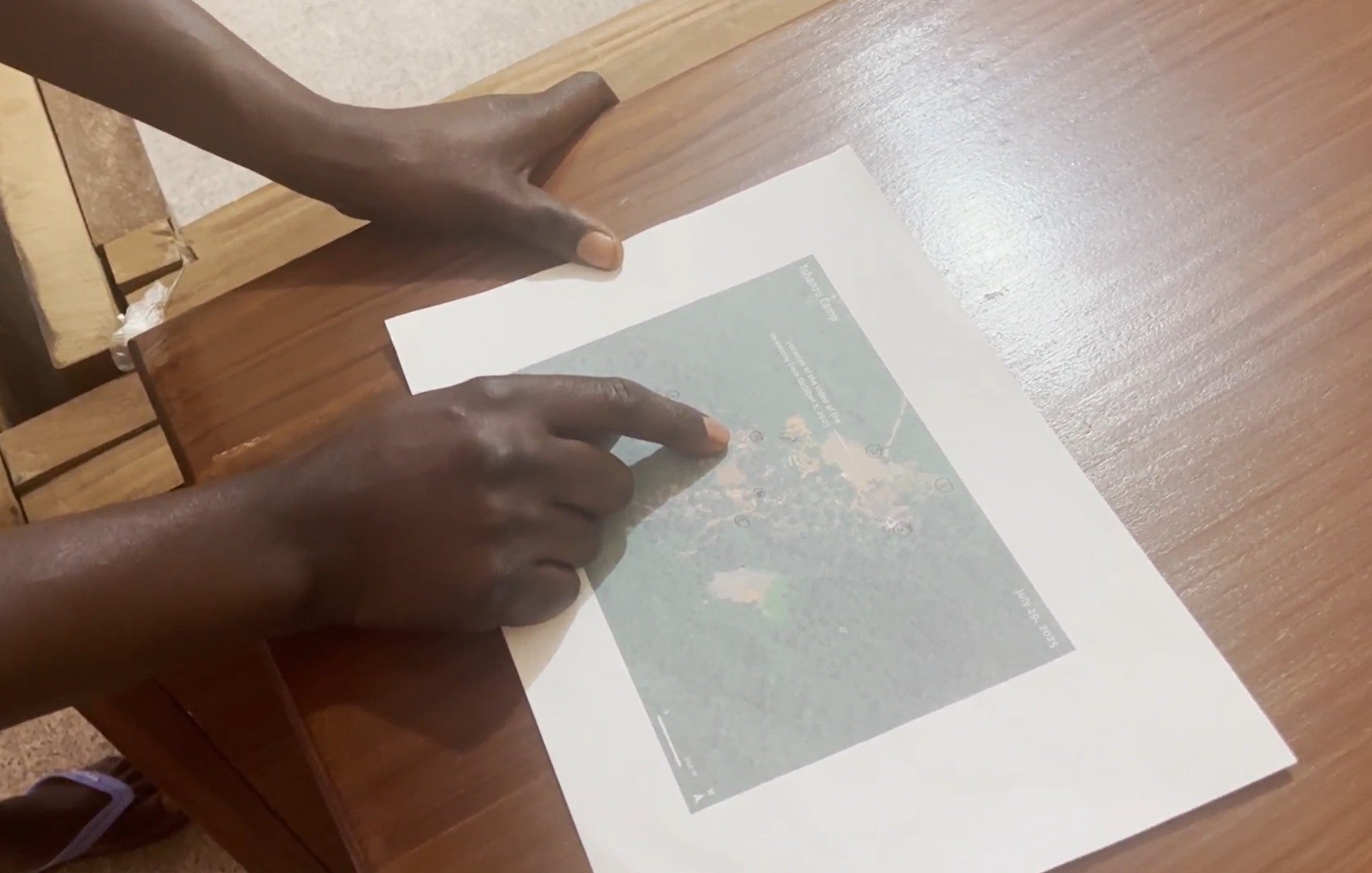 A person points at a printed satellite image