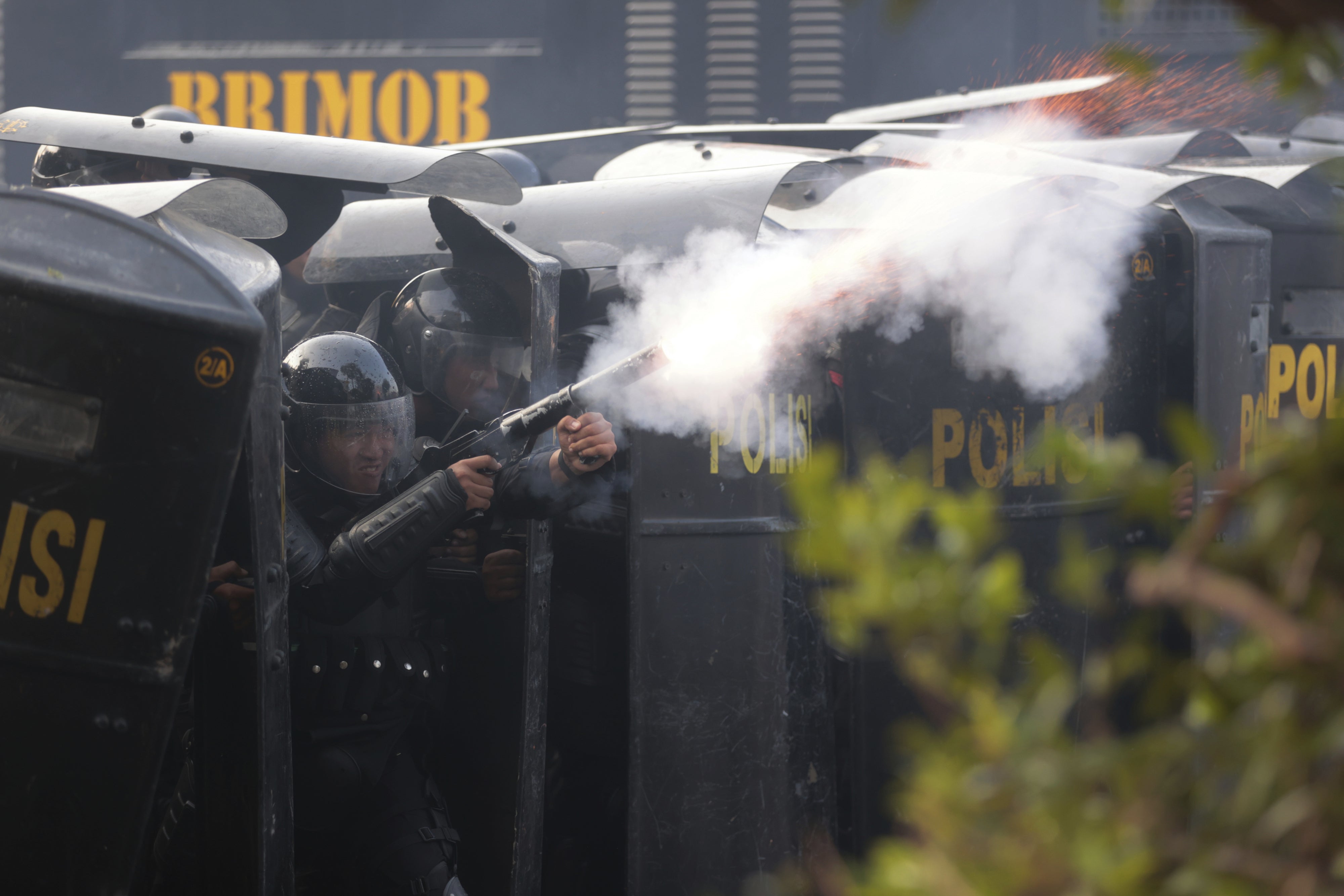 A police officer in protective gear fires tear gas