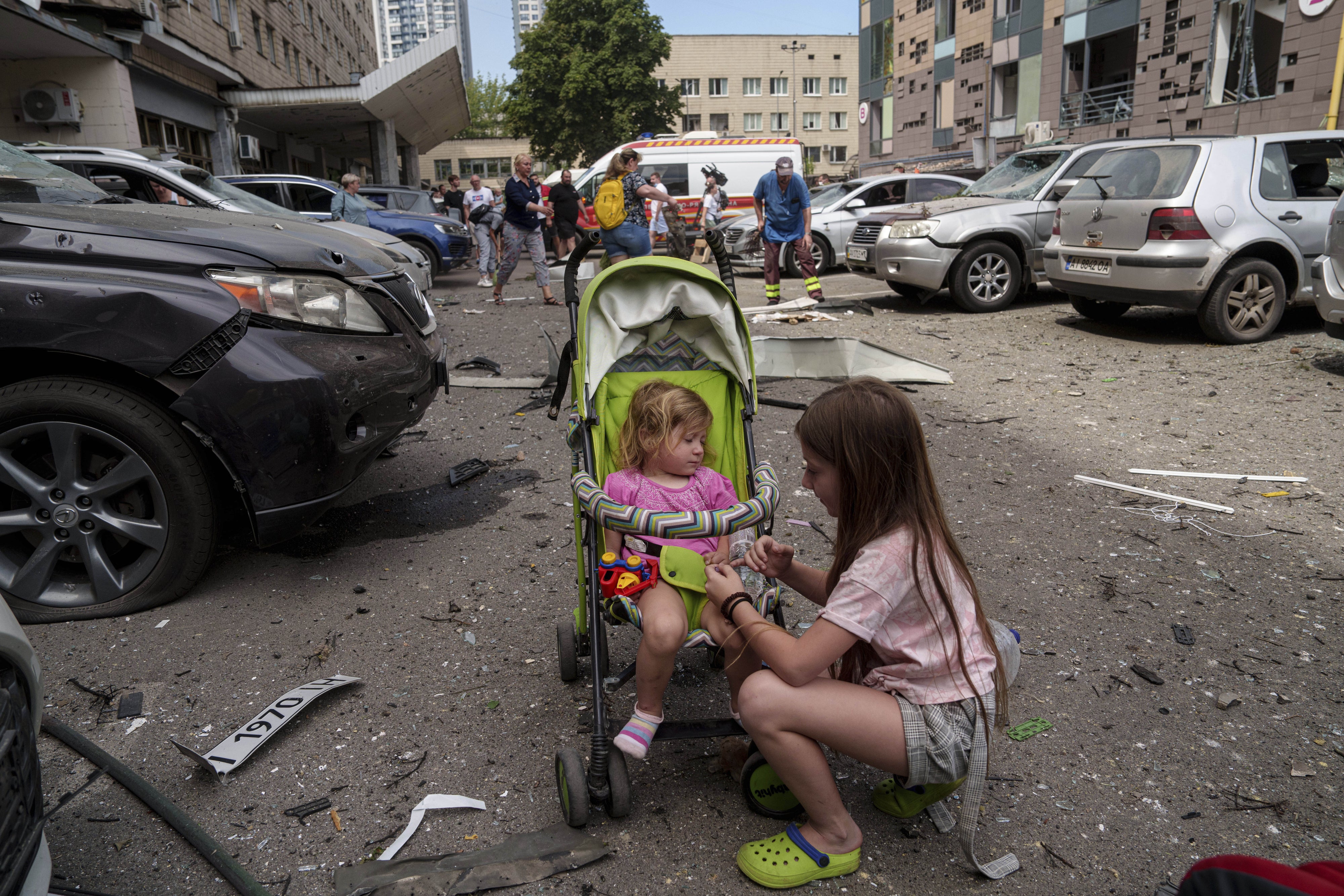 Children wait near the site of Okhmatdyt children’s hospital hit by Russian missiles, in Kyiv, Ukraine, Monday, July 8, 2024.