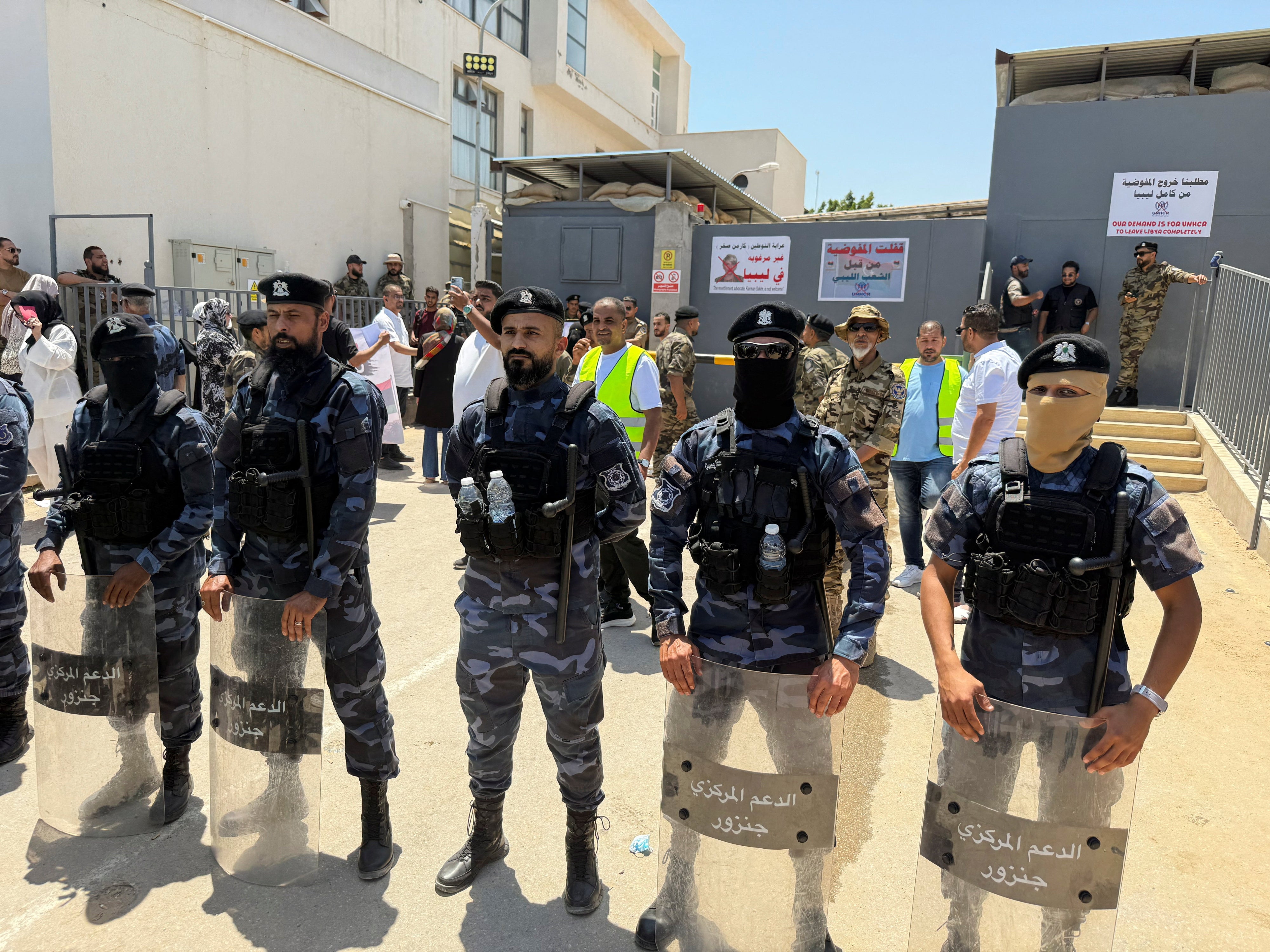 Security personnel stand guard as protesters gather outside the headquarters of the United Nations High Commissioner for Refugees (UNHCR), demanding the organization leave the country and calling for an end to migrant settlement and the deportation of migrants and refugees, in Tripoli, Libya, June 4, 2026. Picture taken with a mobile phone. 