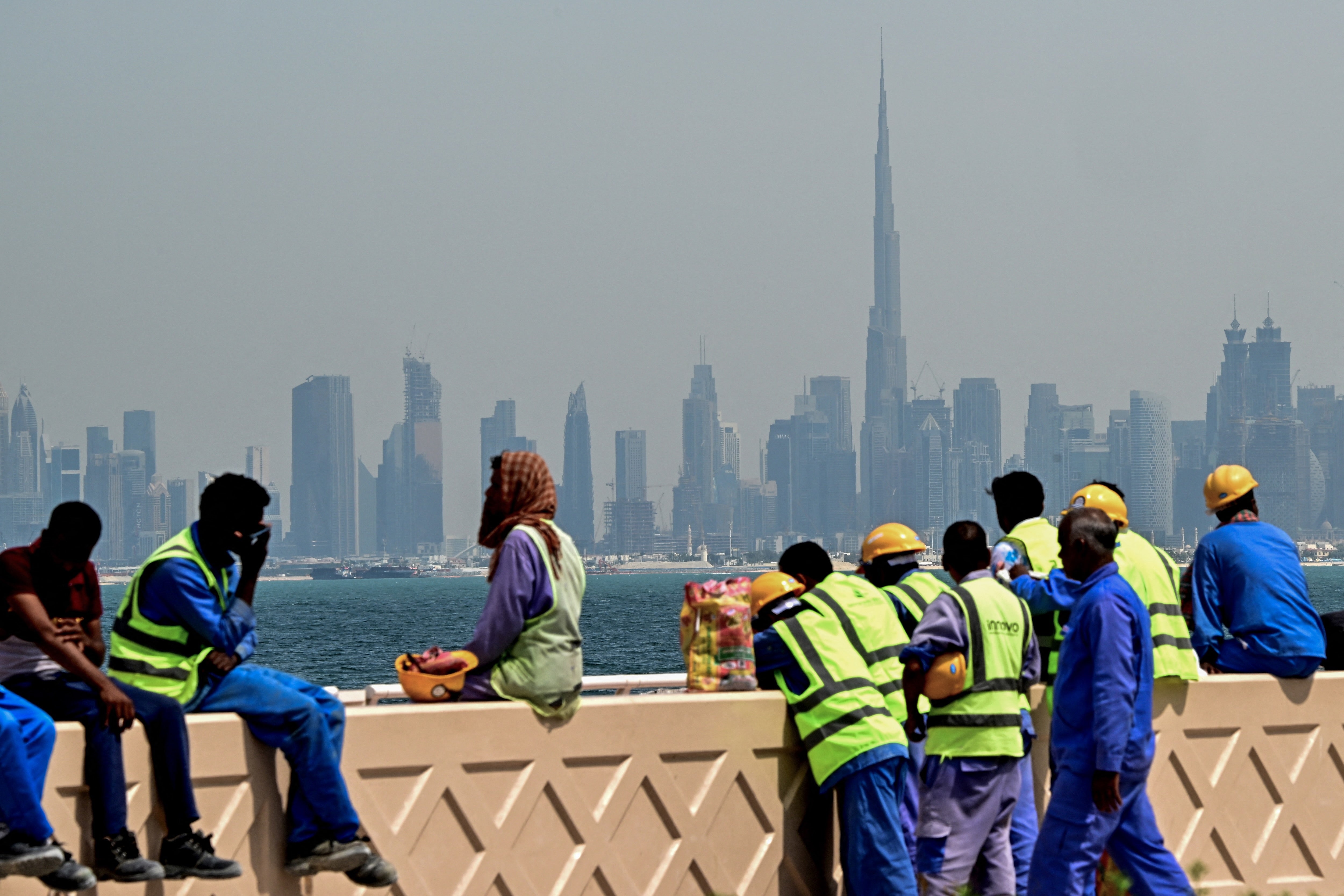 Workers sit on a wall against the backdrop of the city skyline, Dubai, UAE, March 11, 2026.