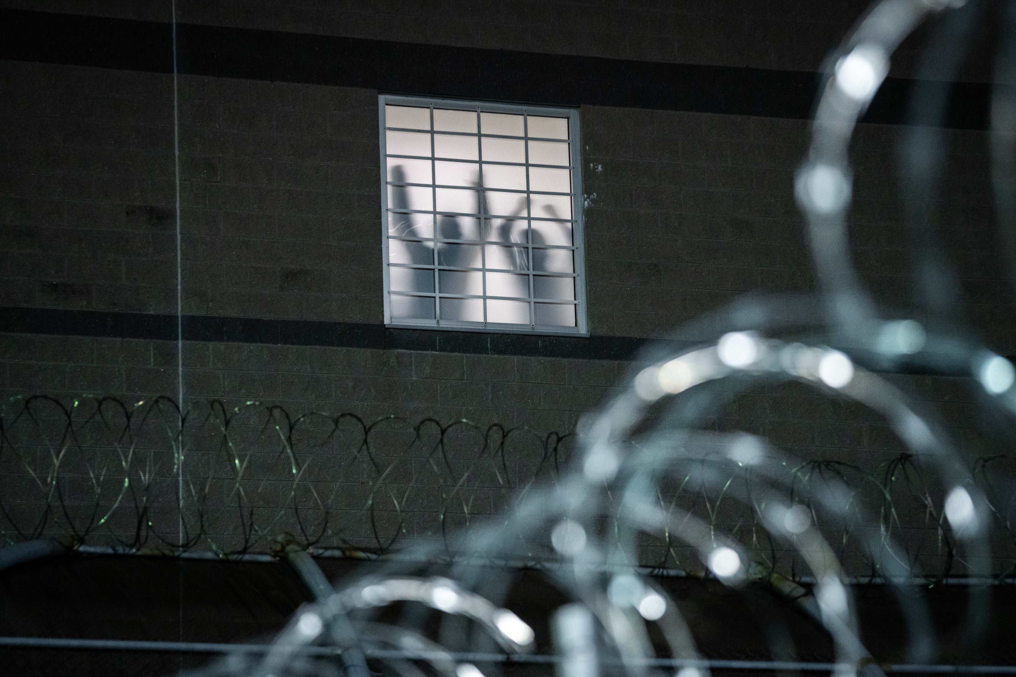 Detainees stand by a window inside the federal immigration center at Delaney Hall