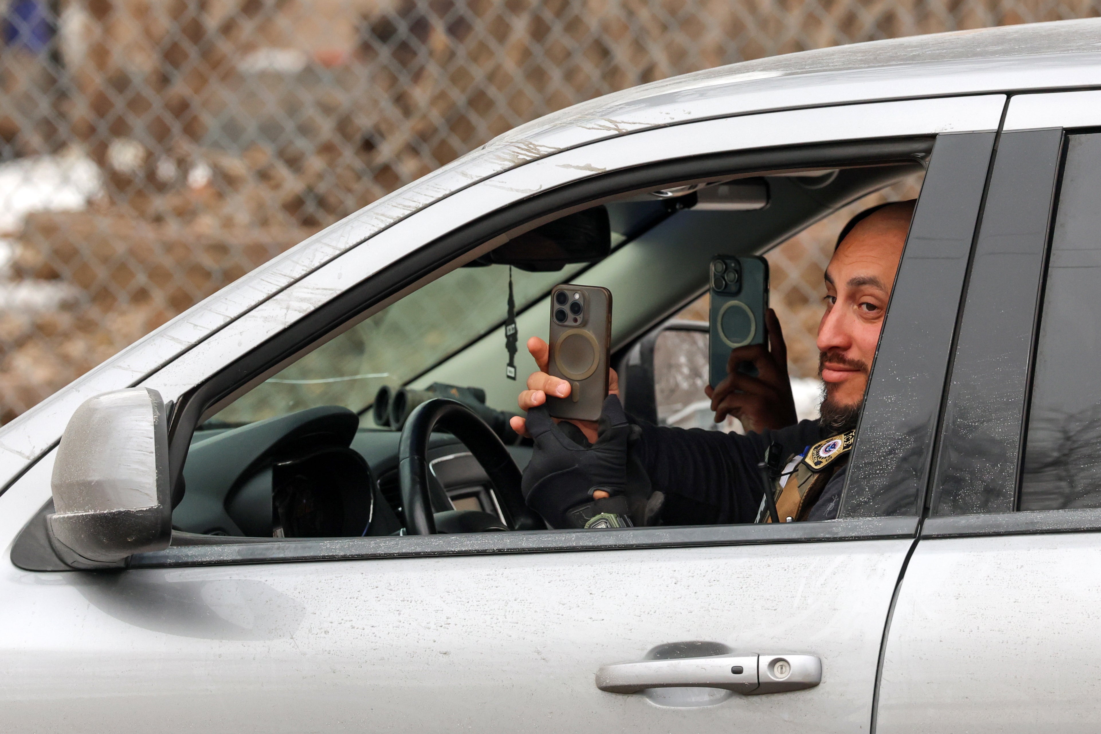 A federal agent appears to record observers from an idling vehicle