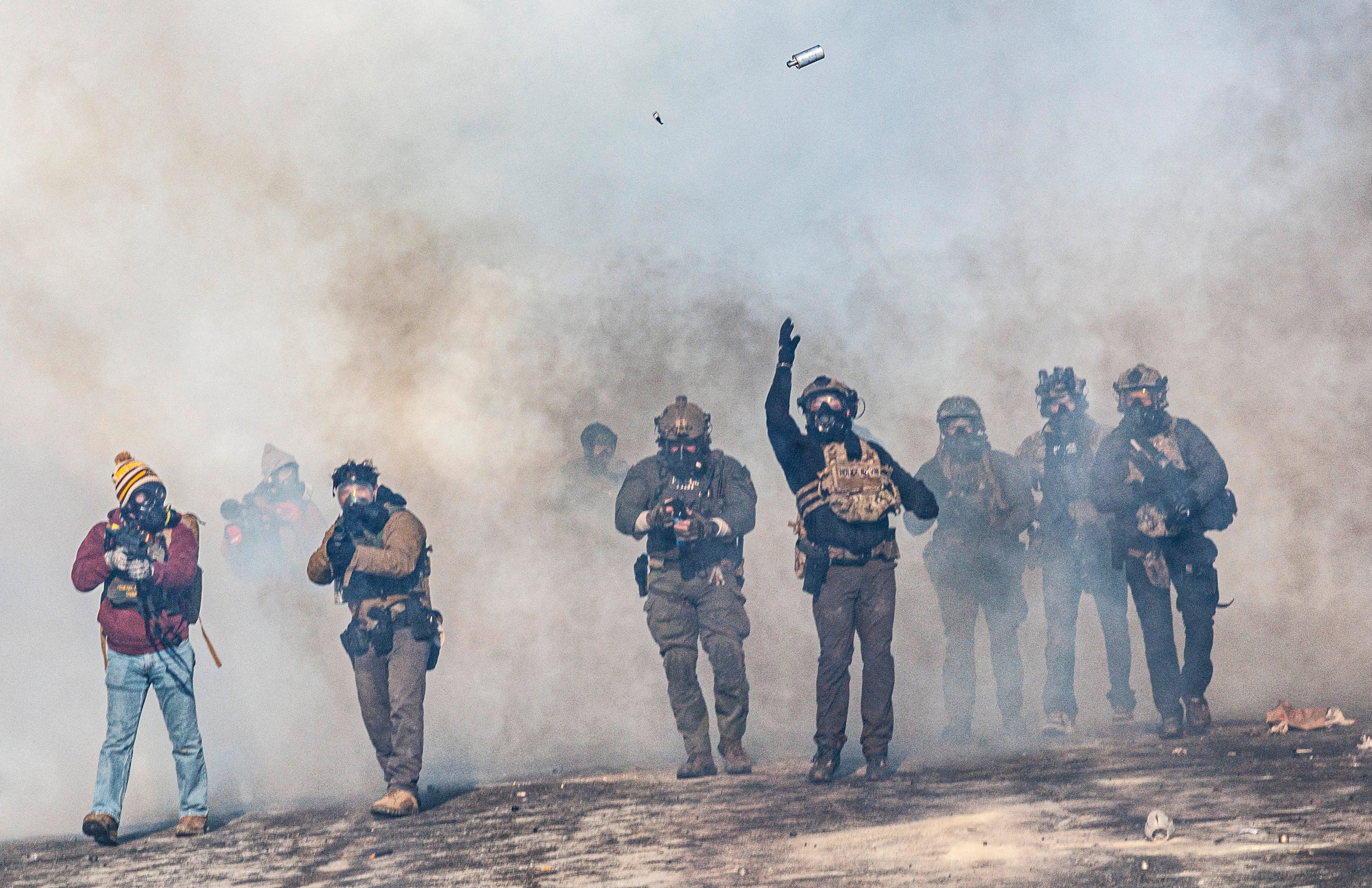 A federal agent lobs a canister towards protesters