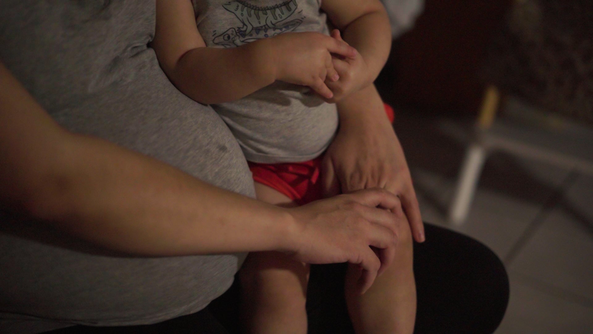 an unidentifiable woman sits holding a child