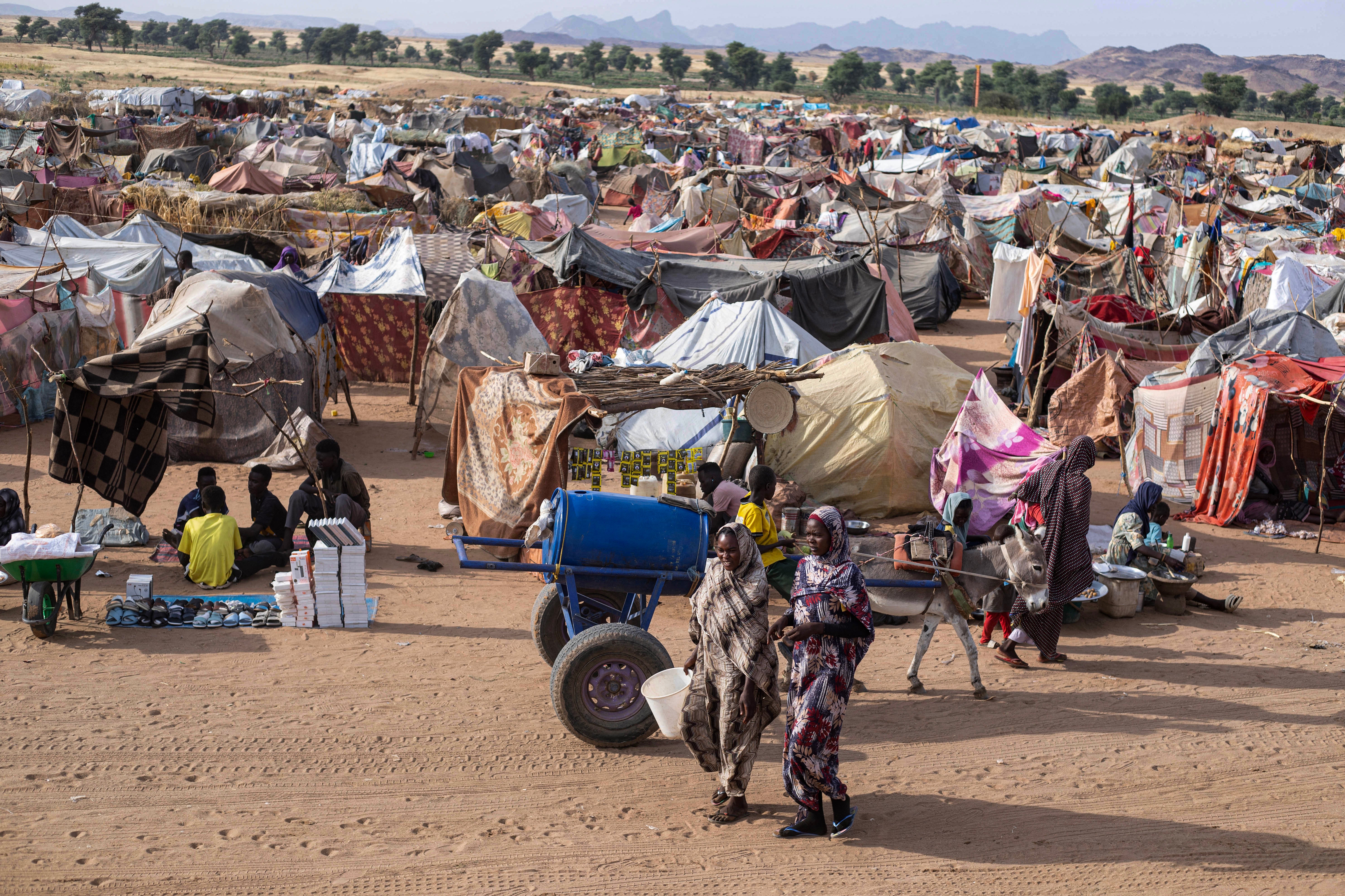 Displaced Sudanese people who fled El-Fasher after the city fell to the Rapid Support Forces (RSF), walk in the Um Yanqur camp, located on the southwestern edge of Tawila, in western Darfur, on November 3, 2025.