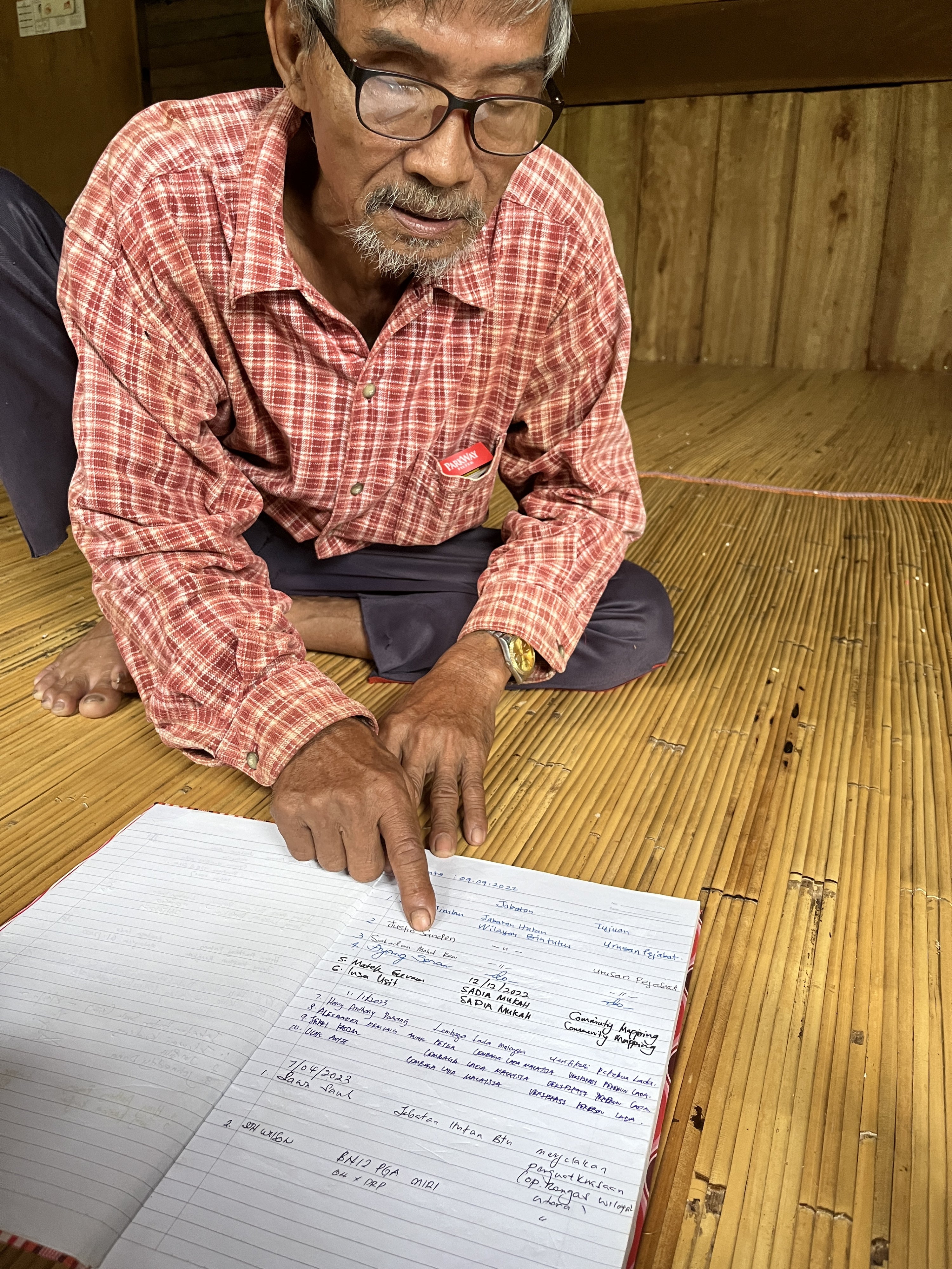 Nyulan Ambang, chief of customs for the Indigenous Iban community of Rumah Jeffery, shows a log of visitors kept by the community to Human Rights Watch researchers visiting their longhouse. The log noted the visit of police and officials from the Sarawak Forest Department who allegedly threatened the community with forced eviction.