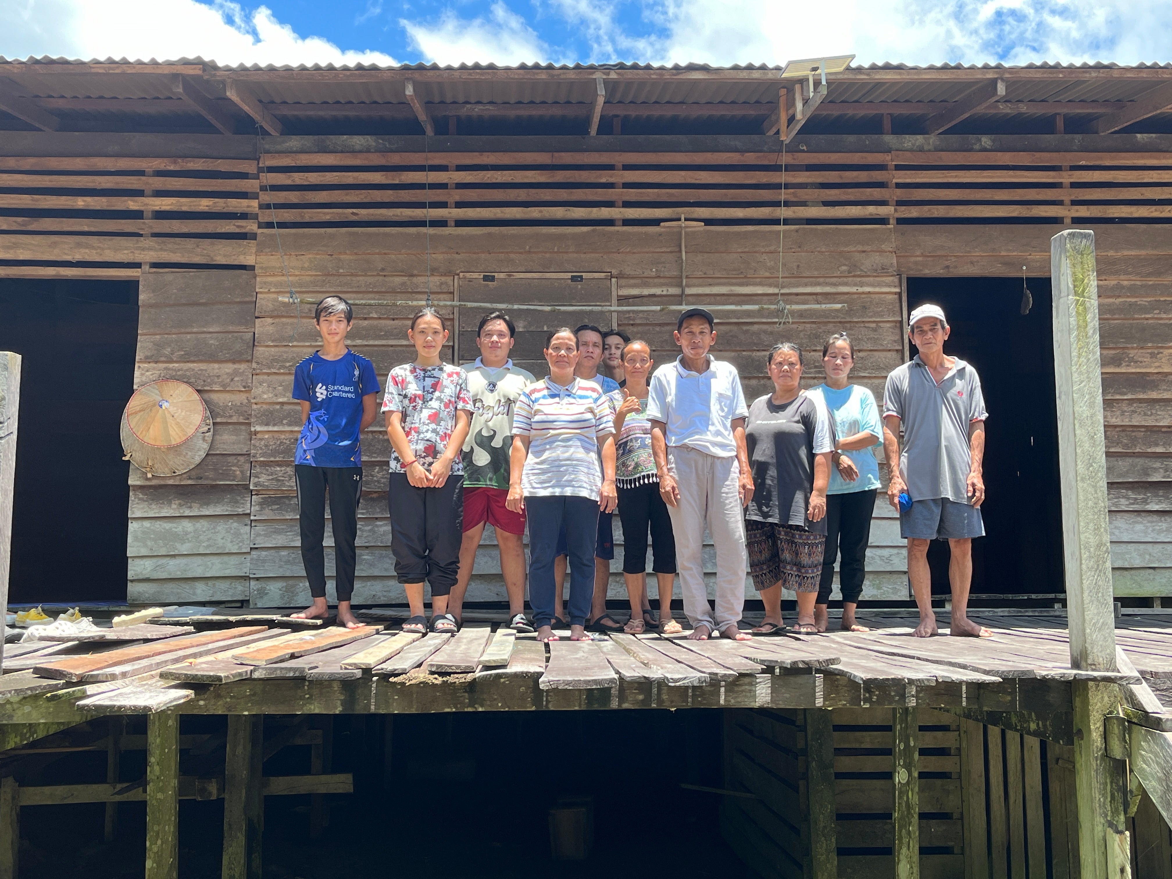 Community members including chief Jeffery (center)  in front of their longhouse in Rumah Jeffery, Sarawak, Malaysia. 