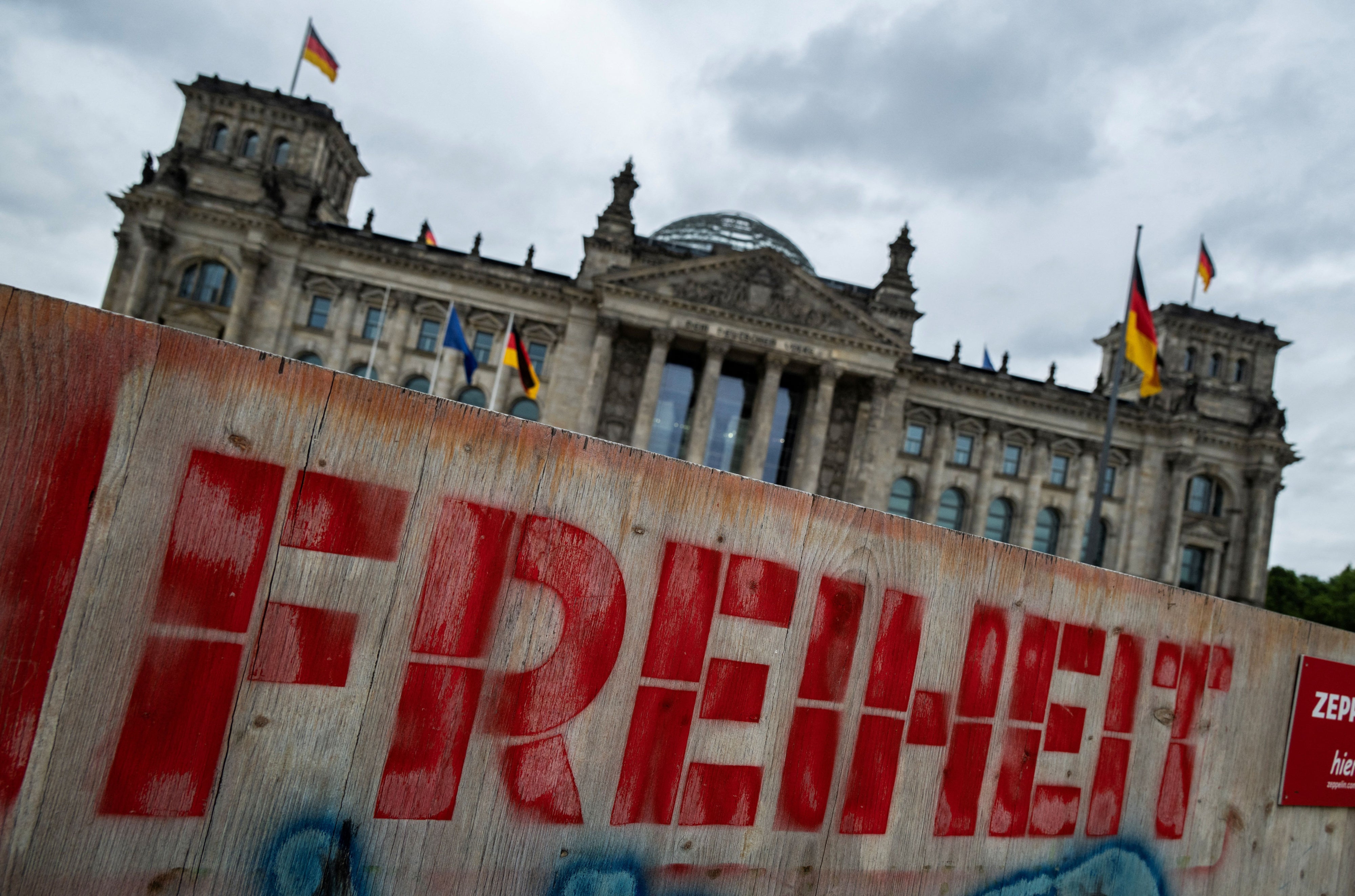 Auf einem Holzzaun vor dem Reichstagsgebäude in Berlin ist das Wort „Freiheit“ zu lesen.