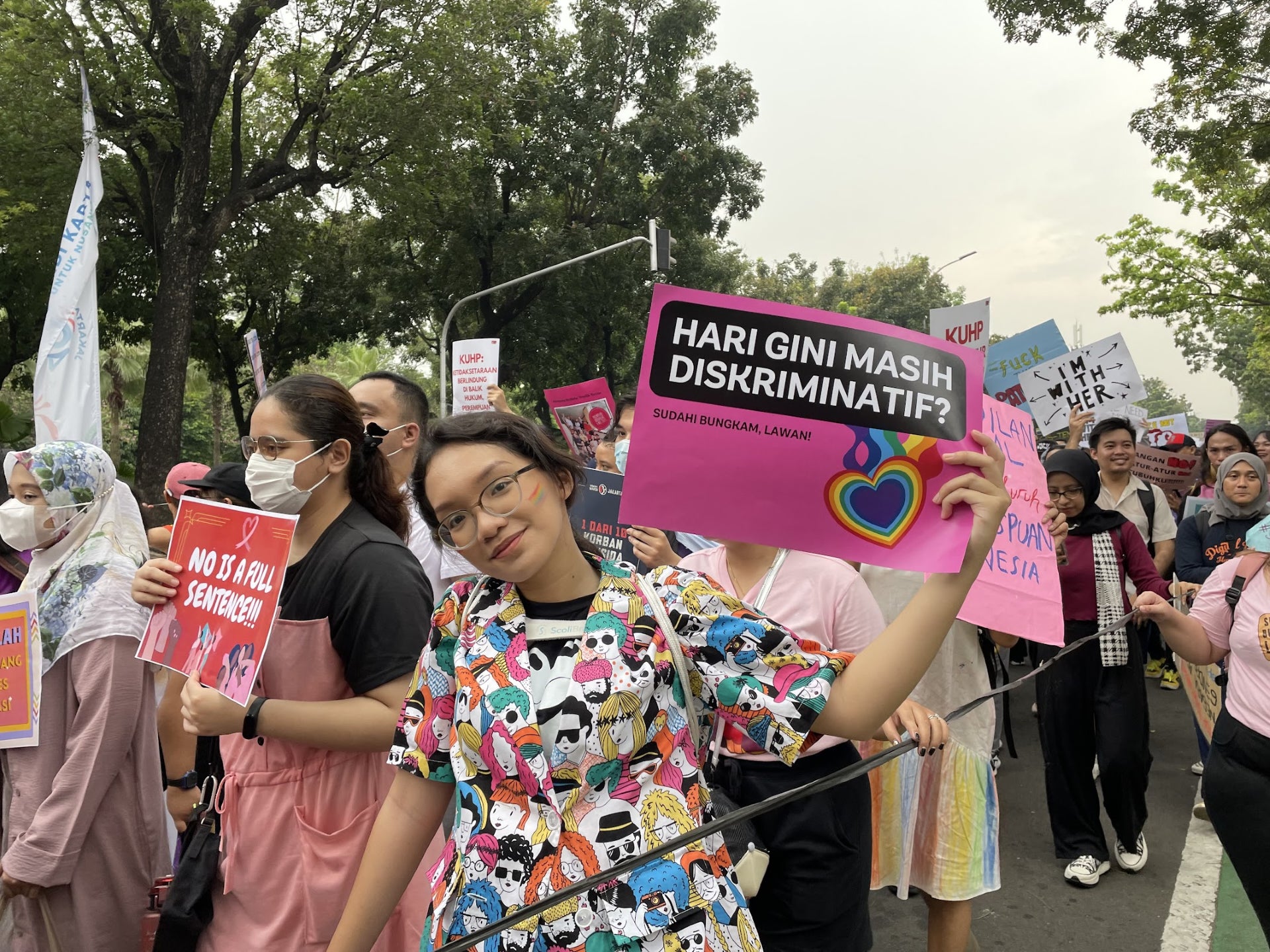 A young protester raises a poster, “Today still discriminatory?” with the love rainbow sign during the Women’s March rally in March 2023 in Jakarta, Indonesia. 