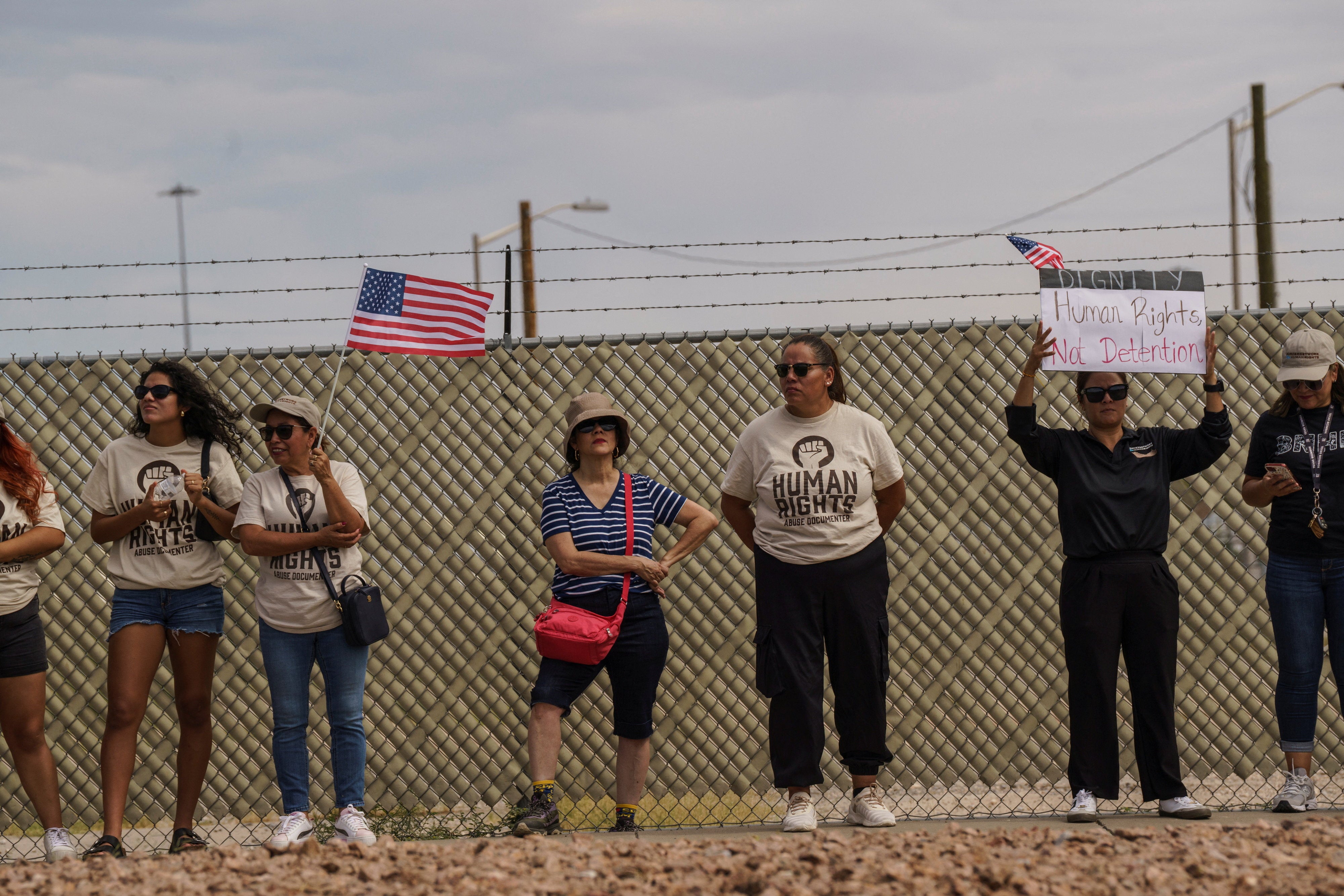 Protesters opposing mass deportations by ICE hold signs during a demonstration held outside of Fort Bliss