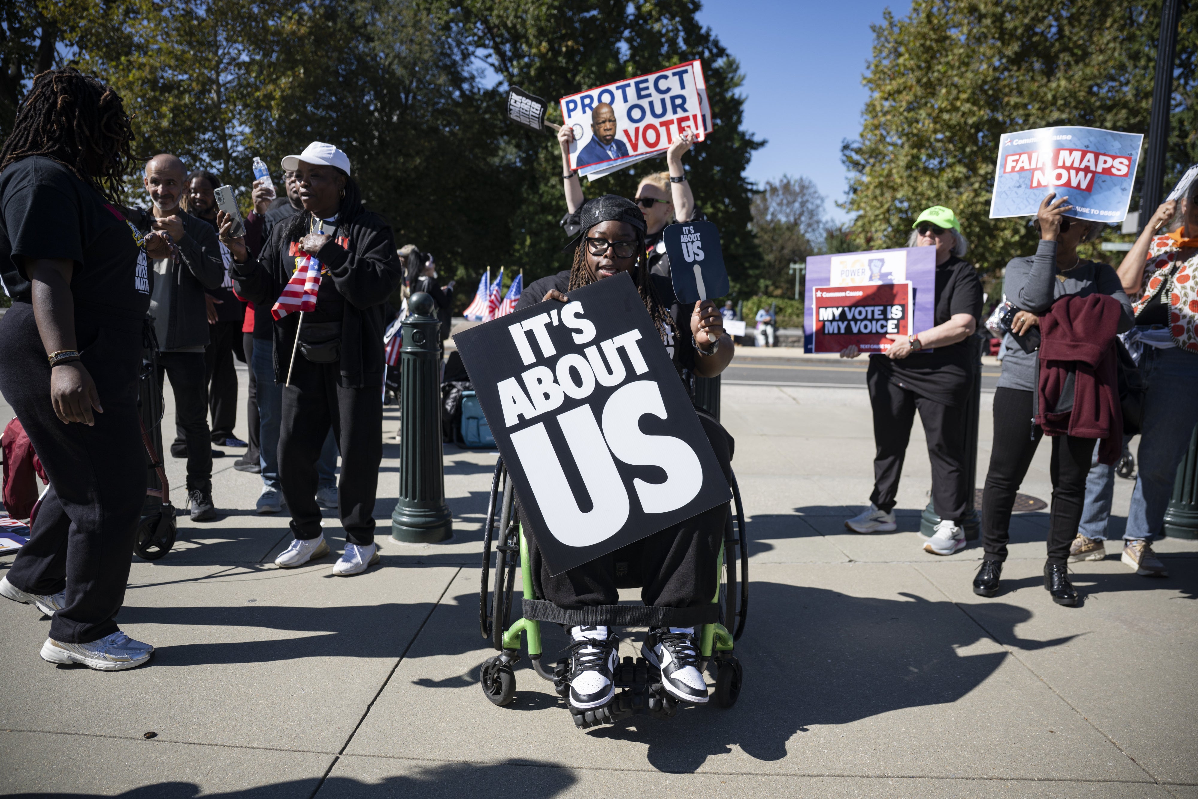 A man in a wheelchair holds a protest sign at a demonstration
