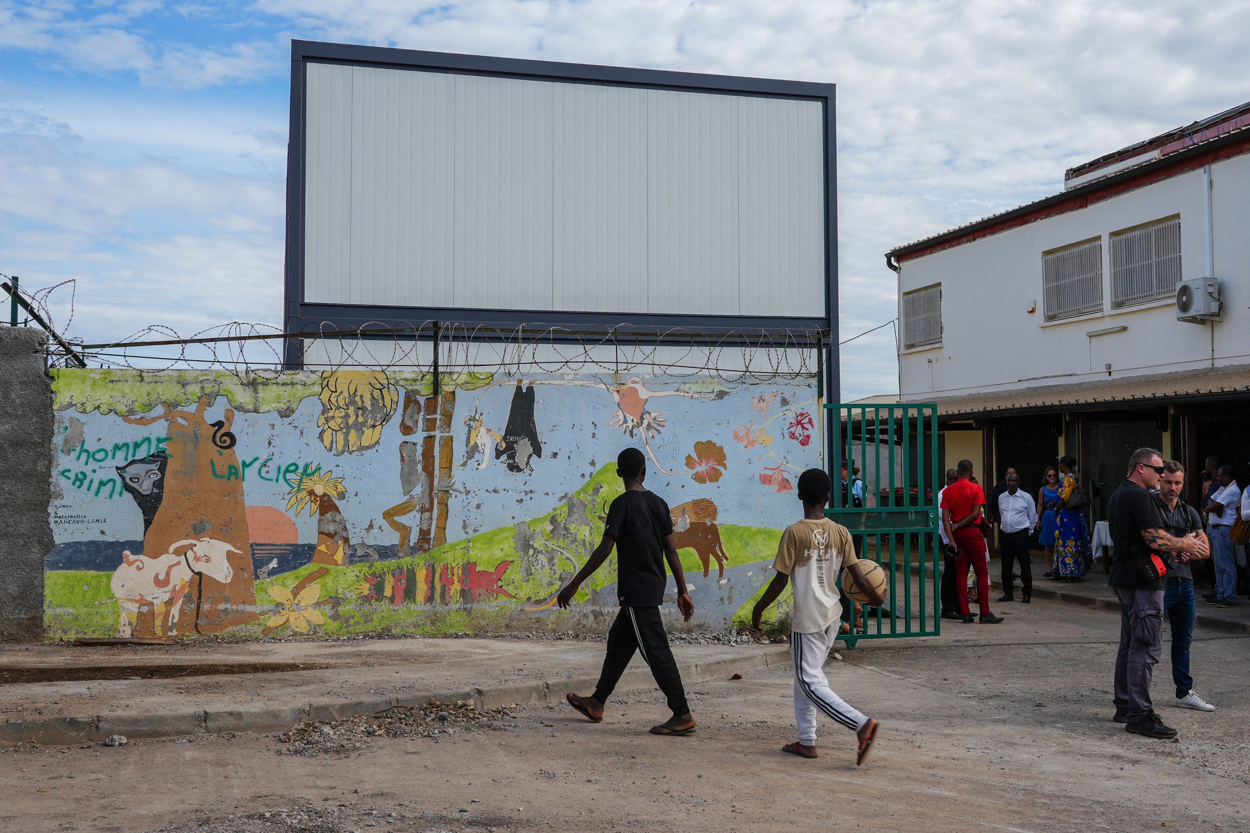 Children walk past modular classrooms built after Cyclone Chido, at the nursery and elementary school of Majicavo-Lamir village on the French overseas territory of Mayotte, on August 18, 2025.