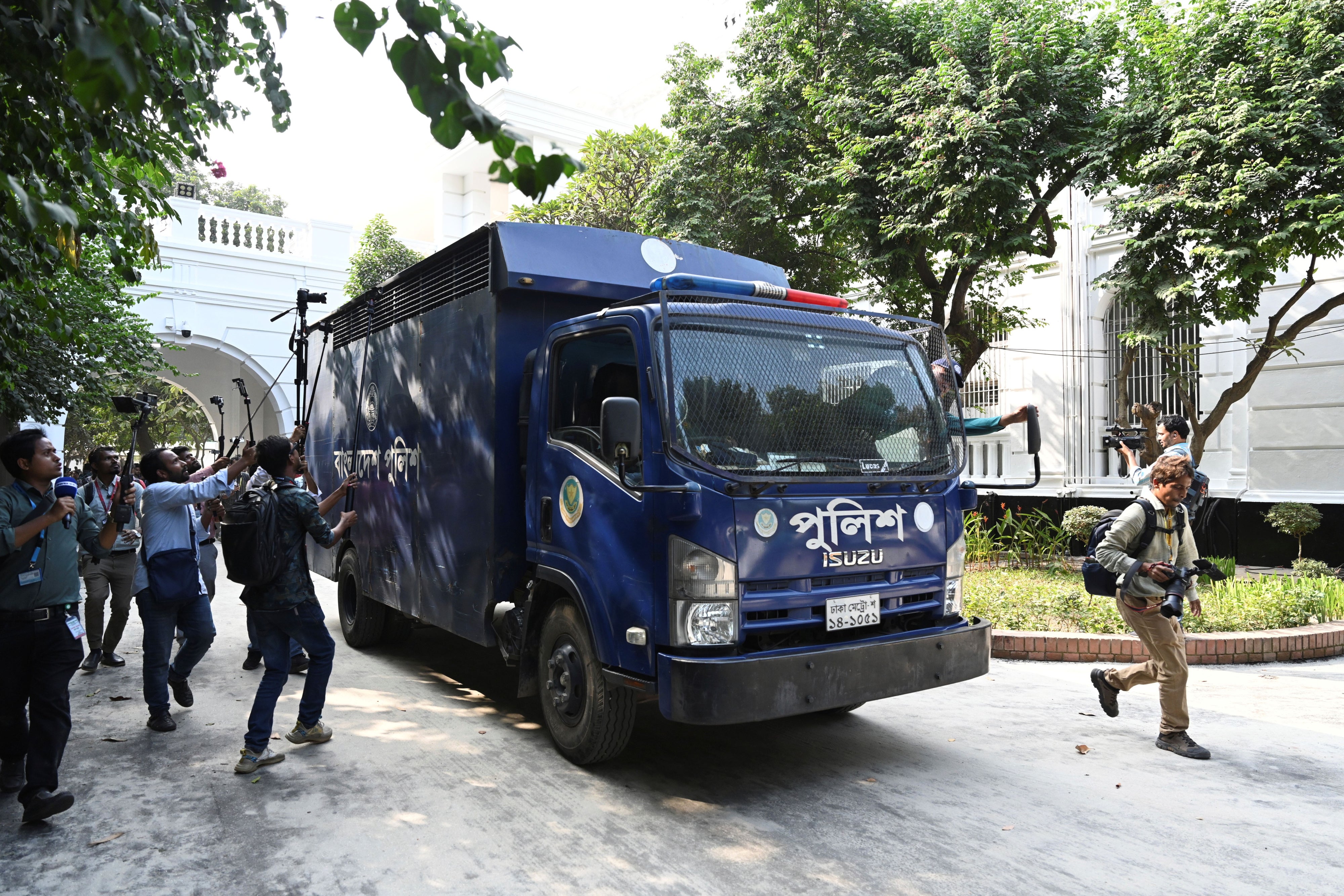 Journalists swarm a blue prison van