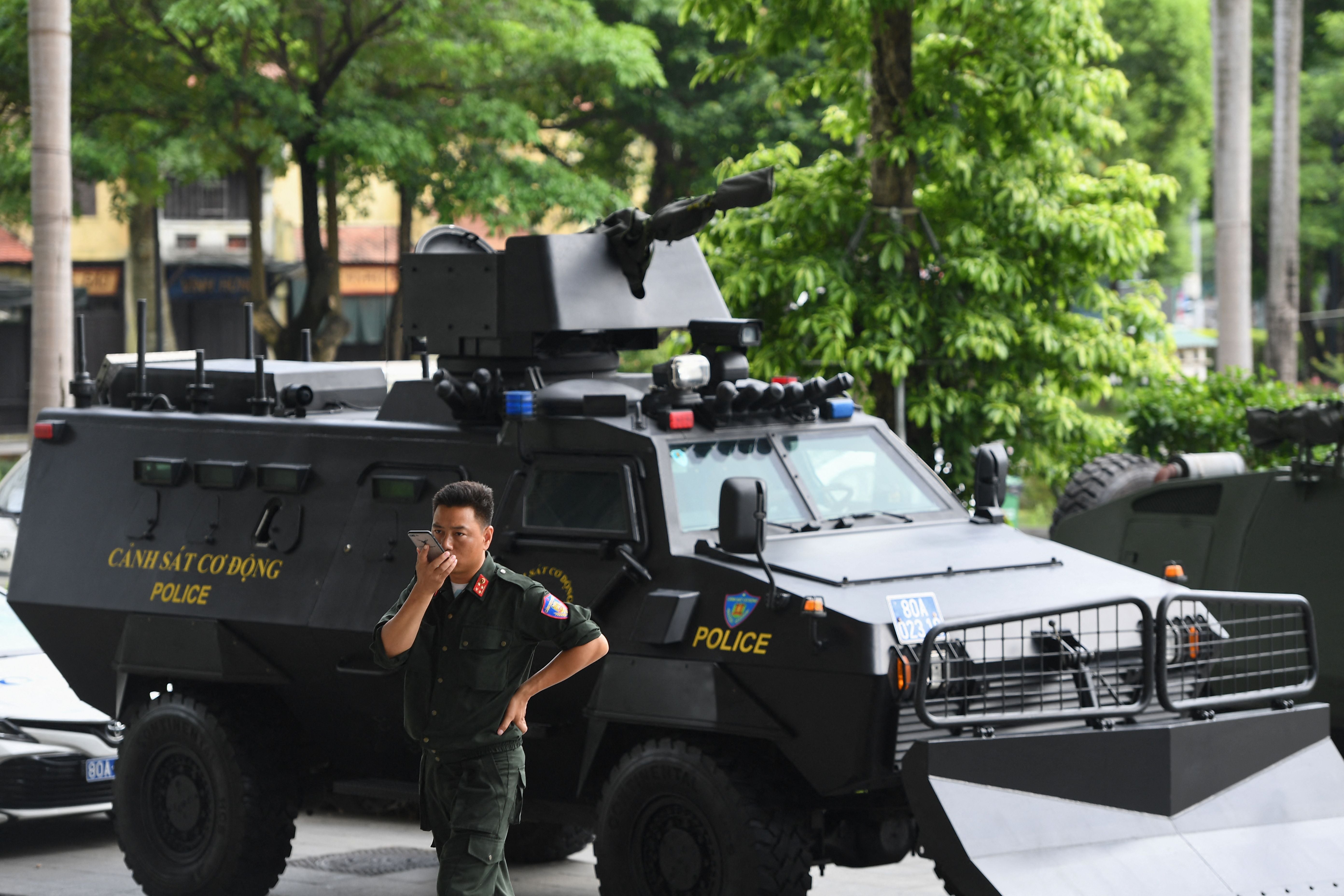 A Vietnamese policeman stands besides an armored vehicle at an exhibition of police equipment in Hanoi, July 20, 2022.