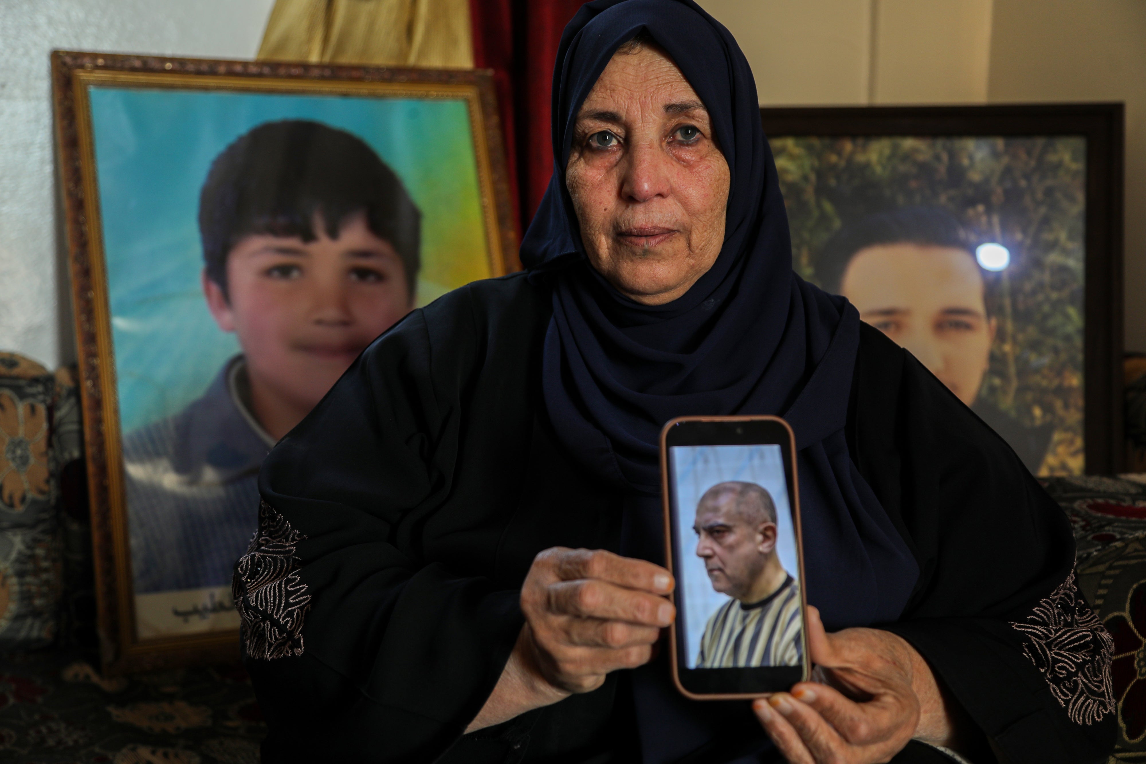 Samira Hahami, une femme syrienne, photographiée en 2026 devant deux photos de son fils Hamza Ali al-Khatib, décédé à l'âge de 13 ans en mai 2011 alors qu'il était détenu par les forces de sécurité du régime de Bachar al-Assad. Son corps portait des traces de torture.