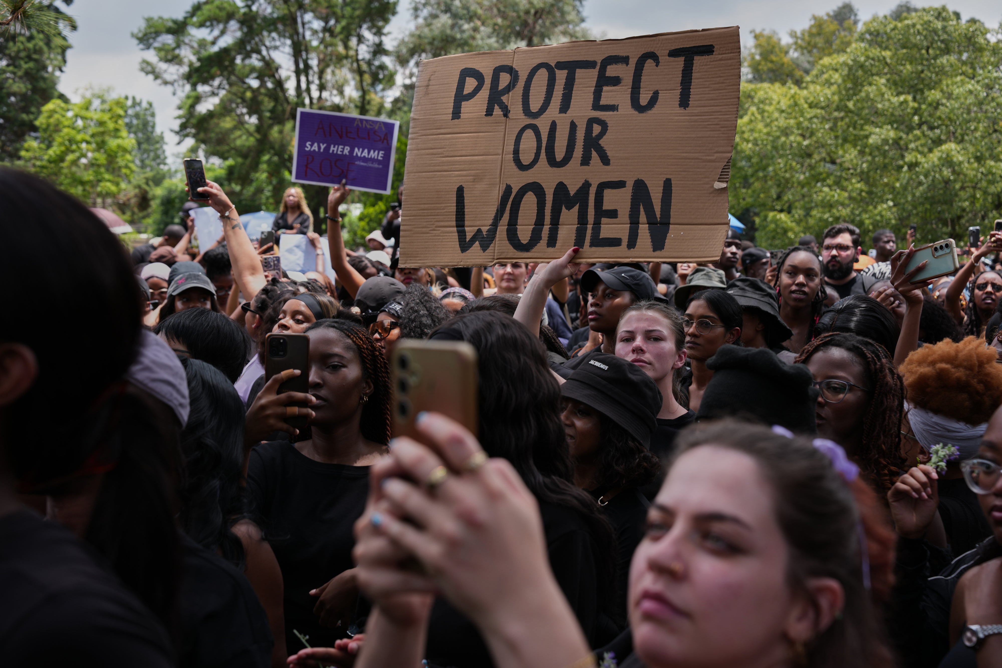 Participants hold signs during a gender-based violence protest at the forecourt of the botanical gardens in Johannesburg, South Africa, November 21, 2025.