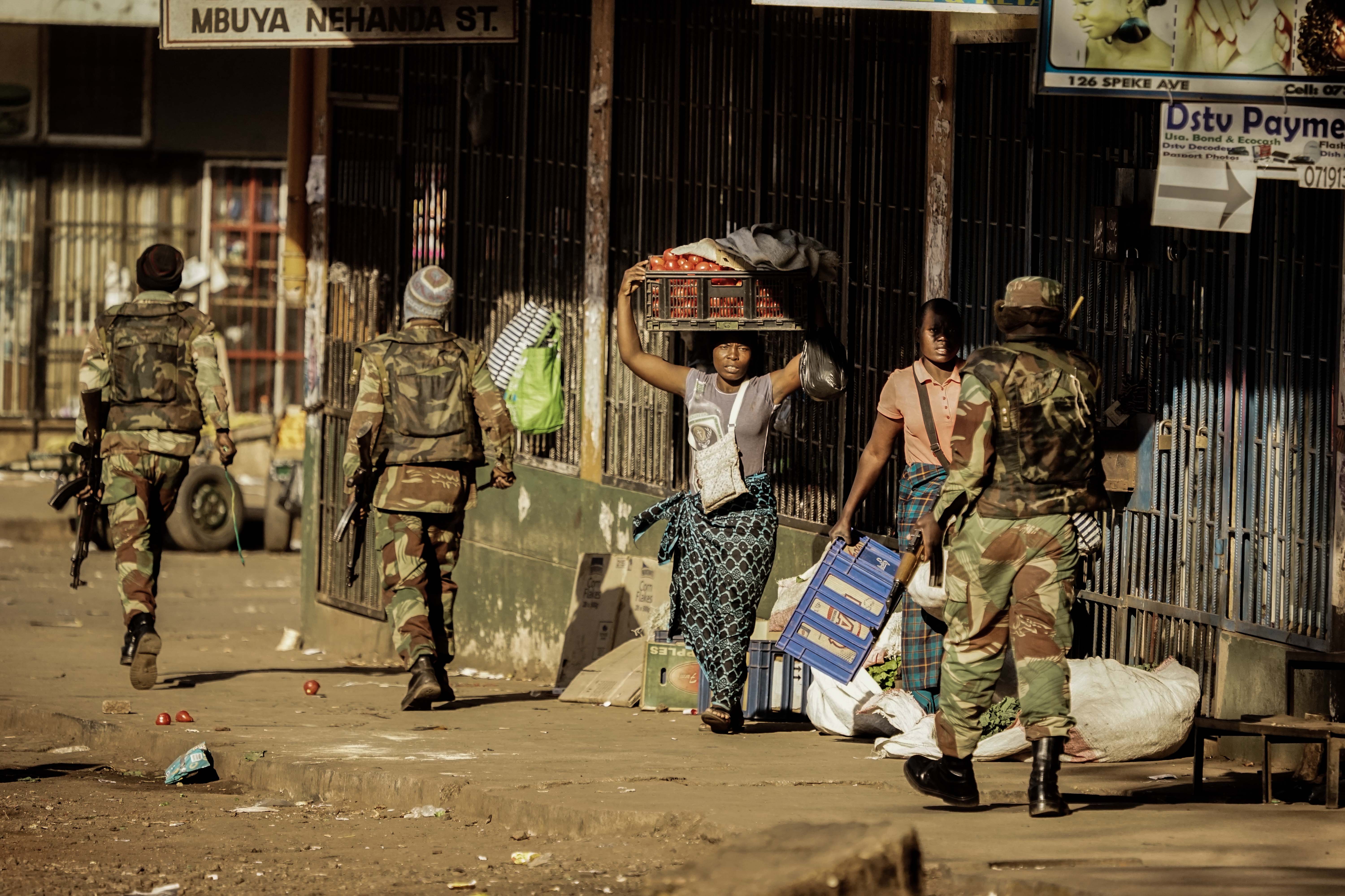A vendor seeks cover as soldiers disperse demonstrators in Harare, Zimbabwe, after protests erupted over alleged fraud in the country's election on August 1, 2018.