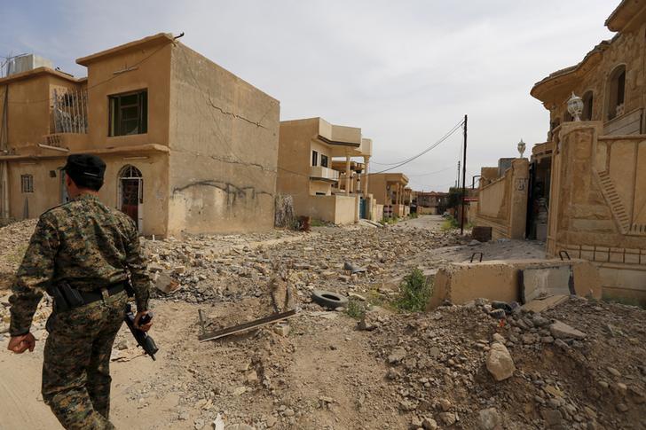 Un membre des forces fidèles au gouvernement irakien traverse une rue déserte et remplie de décombres à Tikrit, au nord de Bagdad, le 1er avril 2015, peu après la fuite des combattants de l’État islamique qui s’étaient précédemment emparés de cette ville.
