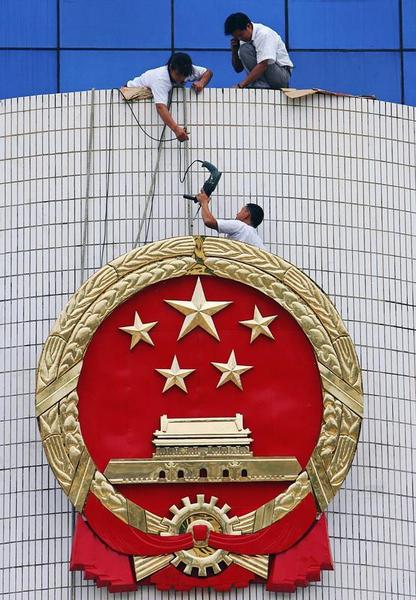 工人正在修整海南省高级人民法院门楣的国徽，中国海南省海口市，2006年8月7日。