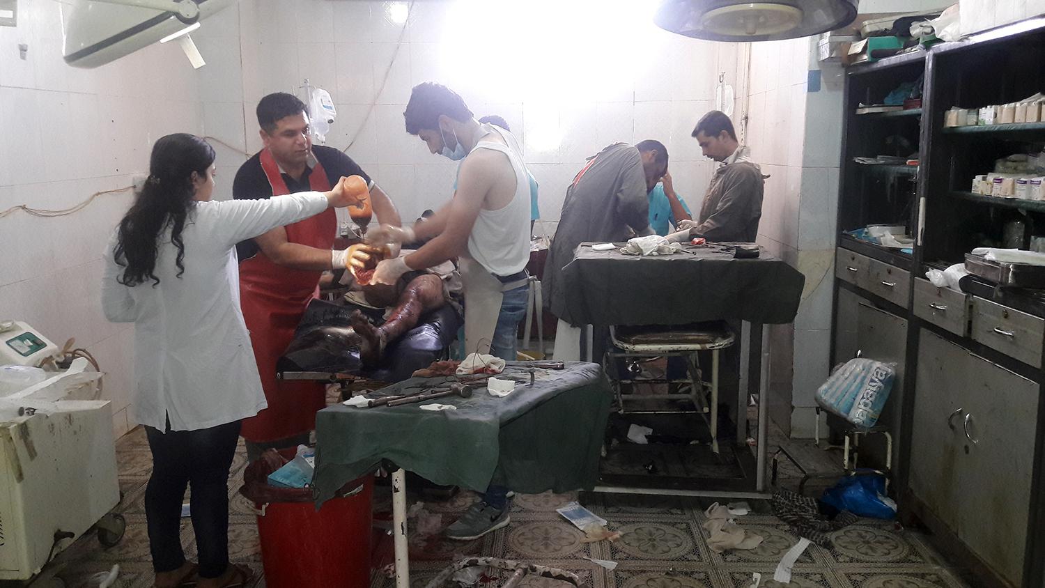 أفراد الطاقم الطبي في مستشفى الأمل في كوباني يعالجون أبا وابنه أصيبا بانفجار عبوة ناسفة أثناء محاولتهما الفرار من مناطق سيطرة داعش في منبج في أغسطس/آب. 